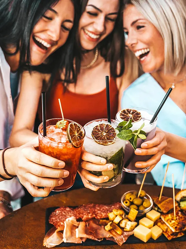 Joyful celebration with friends enjoying vibrant cocktails and an appetizing charcuterie board.