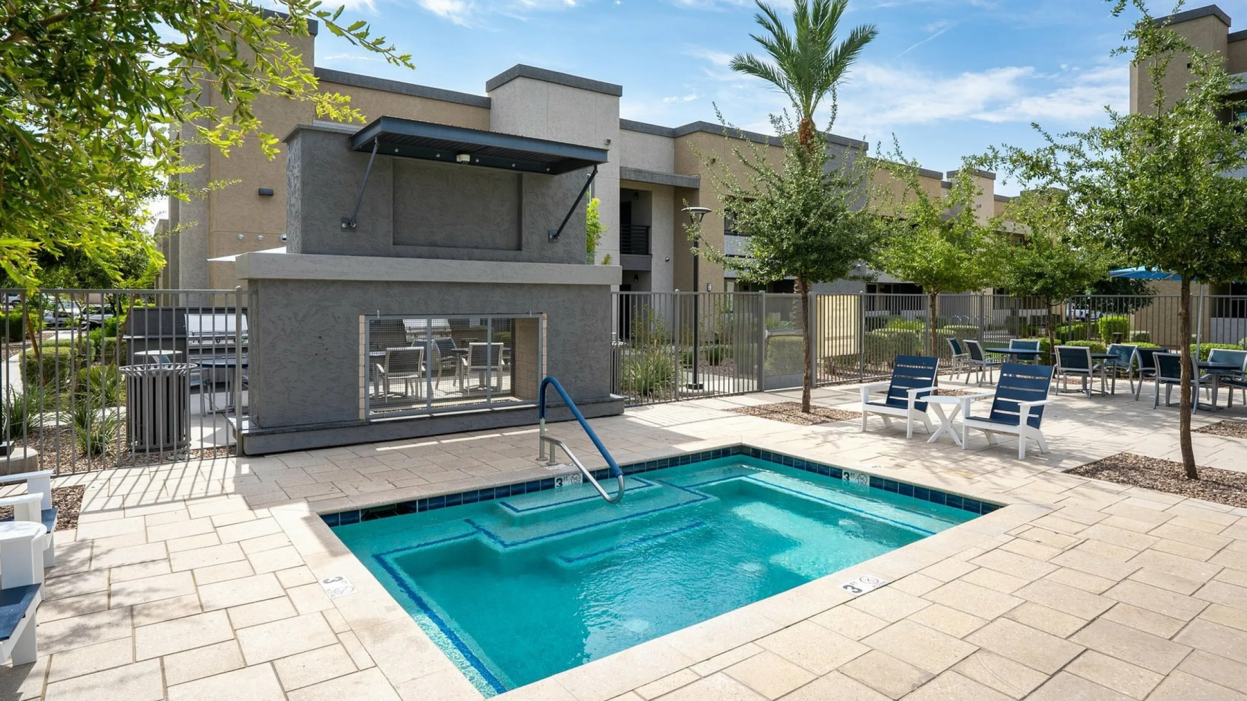 Inviting outdoor area with a sparkling blue pool, stylish lounge chairs, and modern architectural backdrop under a sunny sky.
