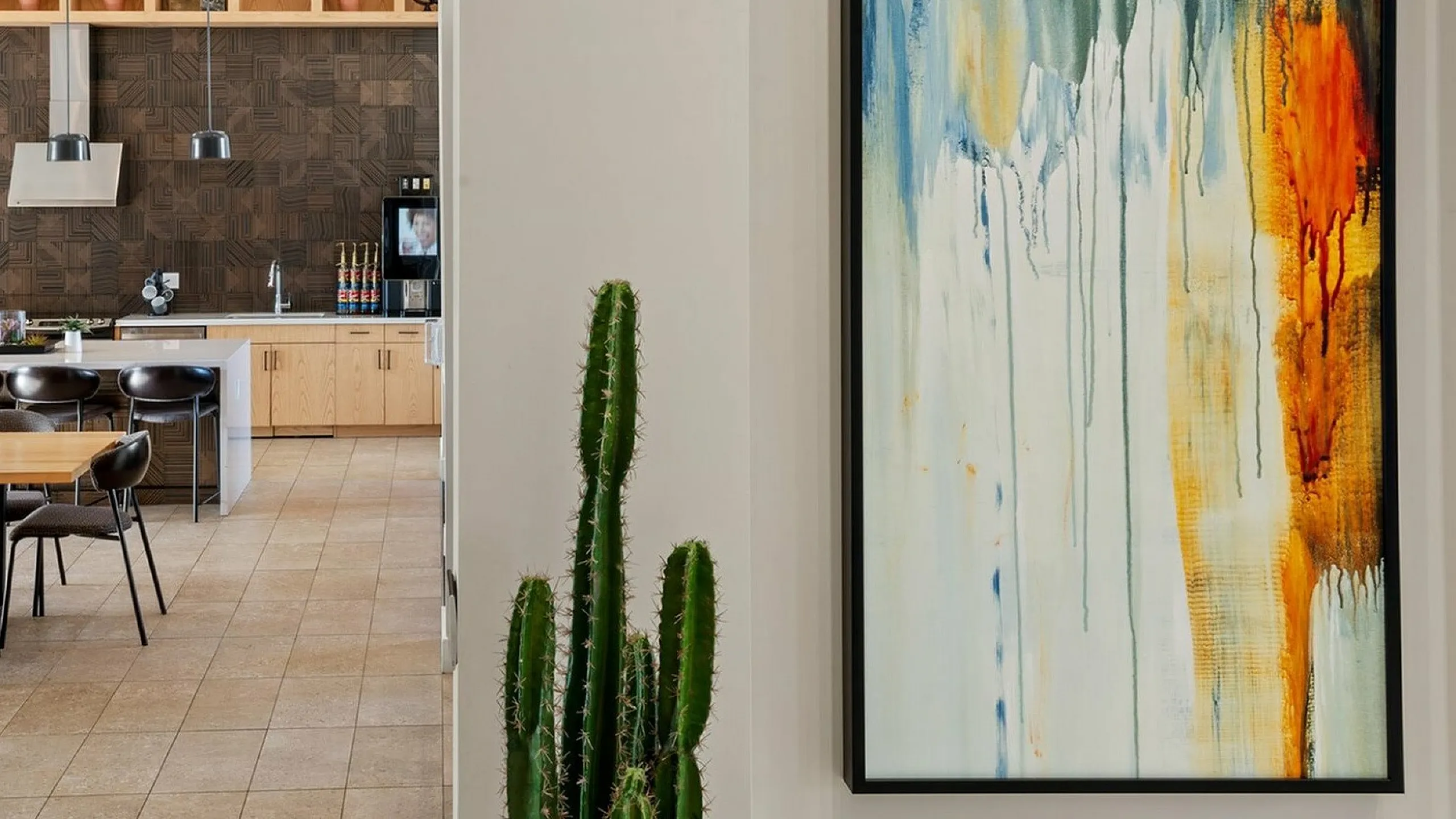 Chic open-concept kitchen featuring elegant pendant lighting, modern cabinetry, and vibrant abstract artwork, perfect for stylish living.