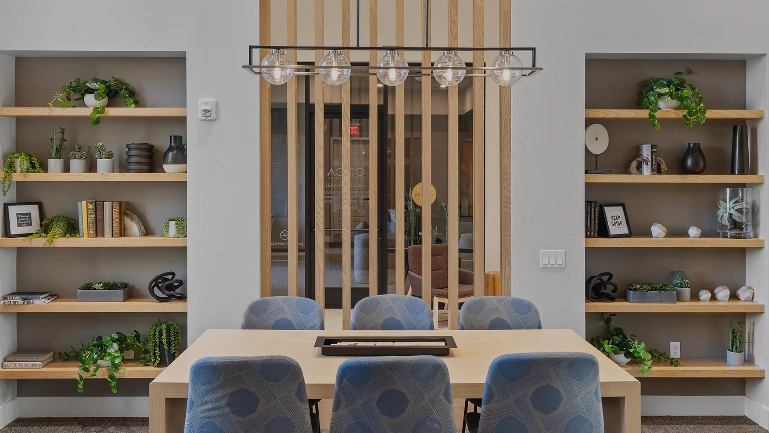 Chic contemporary dining area with elegant light fixture and stylish shelving, perfect for modern living.