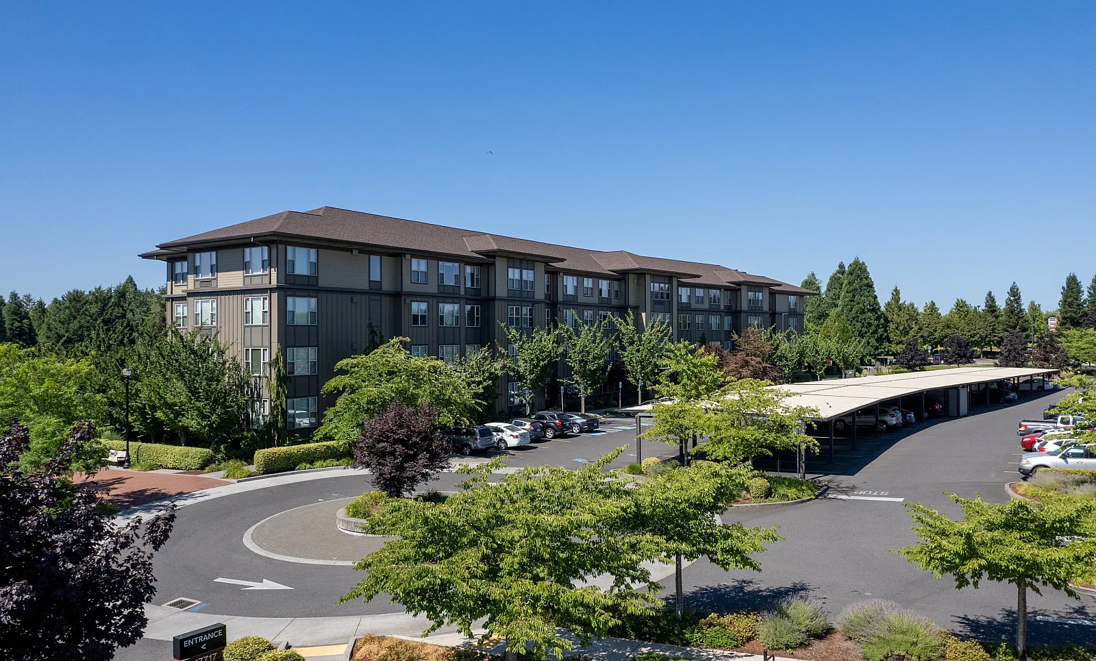 Charming apartment complex with lush greenery, ample parking, and a welcoming entrance, perfect for modern living.