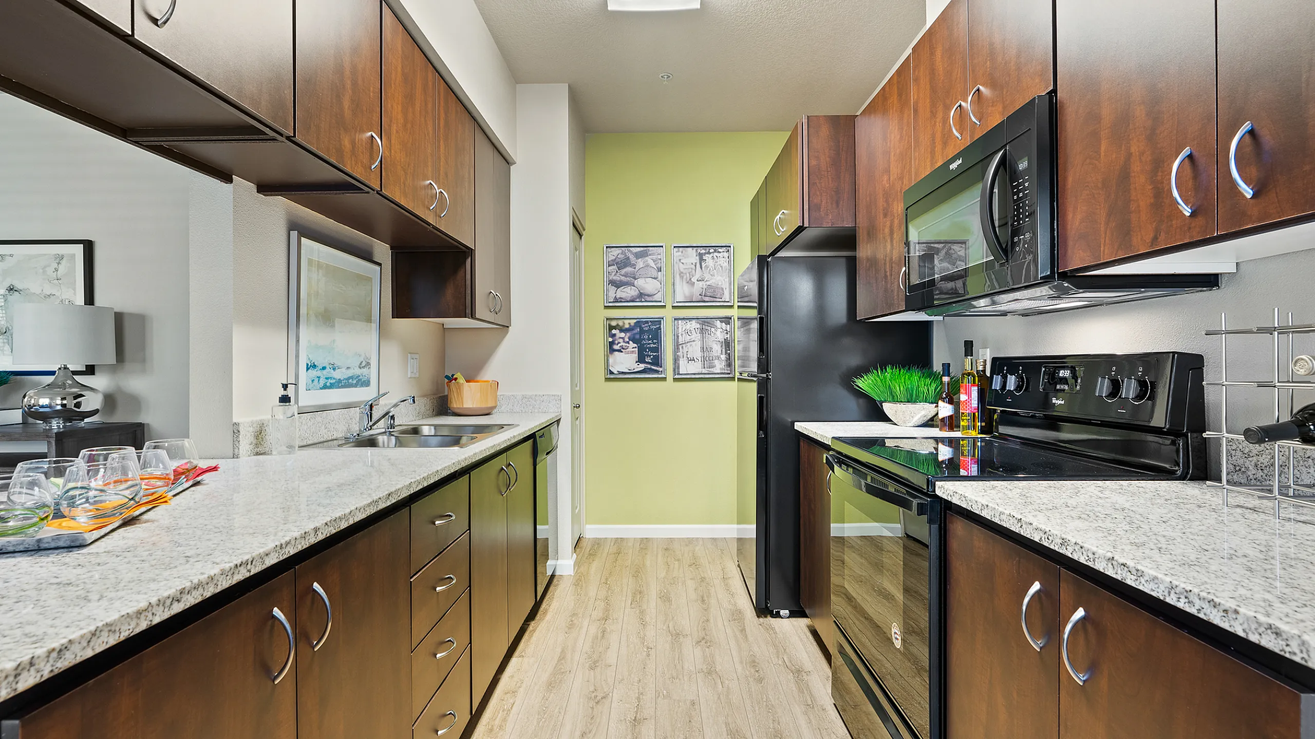 Modern kitchen with sleek dark wood cabinets, granite countertops, and stainless steel appliances in a stylish apartment unit.