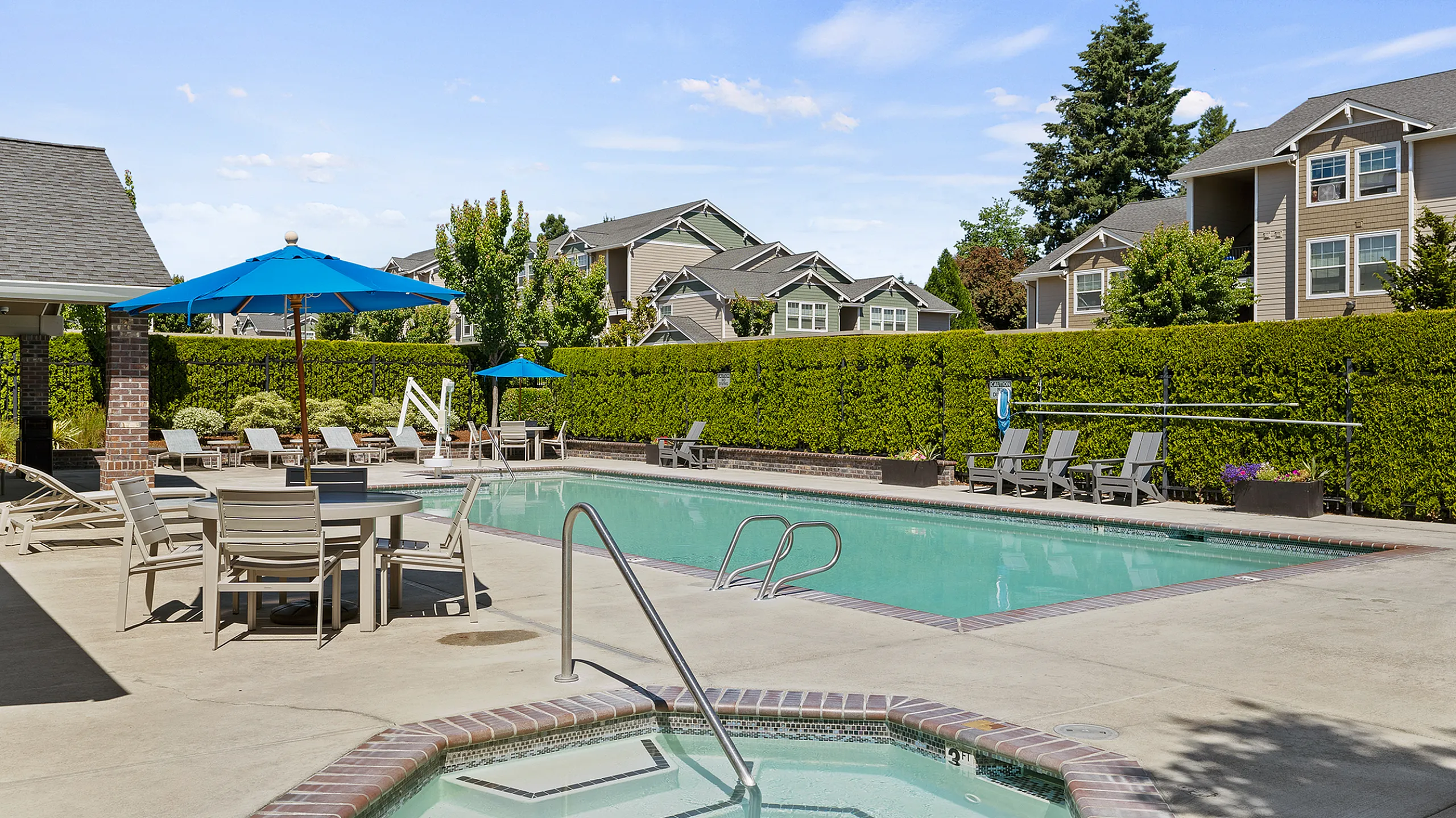 Inviting outdoor swimming pool area with cozy seating and vibrant blue umbrellas, perfect for relaxation in a serene residential setting.
