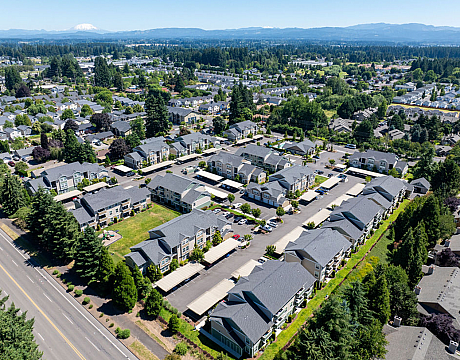 Expansive aerial view of a vibrant apartment complex nestled in lush greenery, offering a picturesque blend of modern living and scenic surroundings.