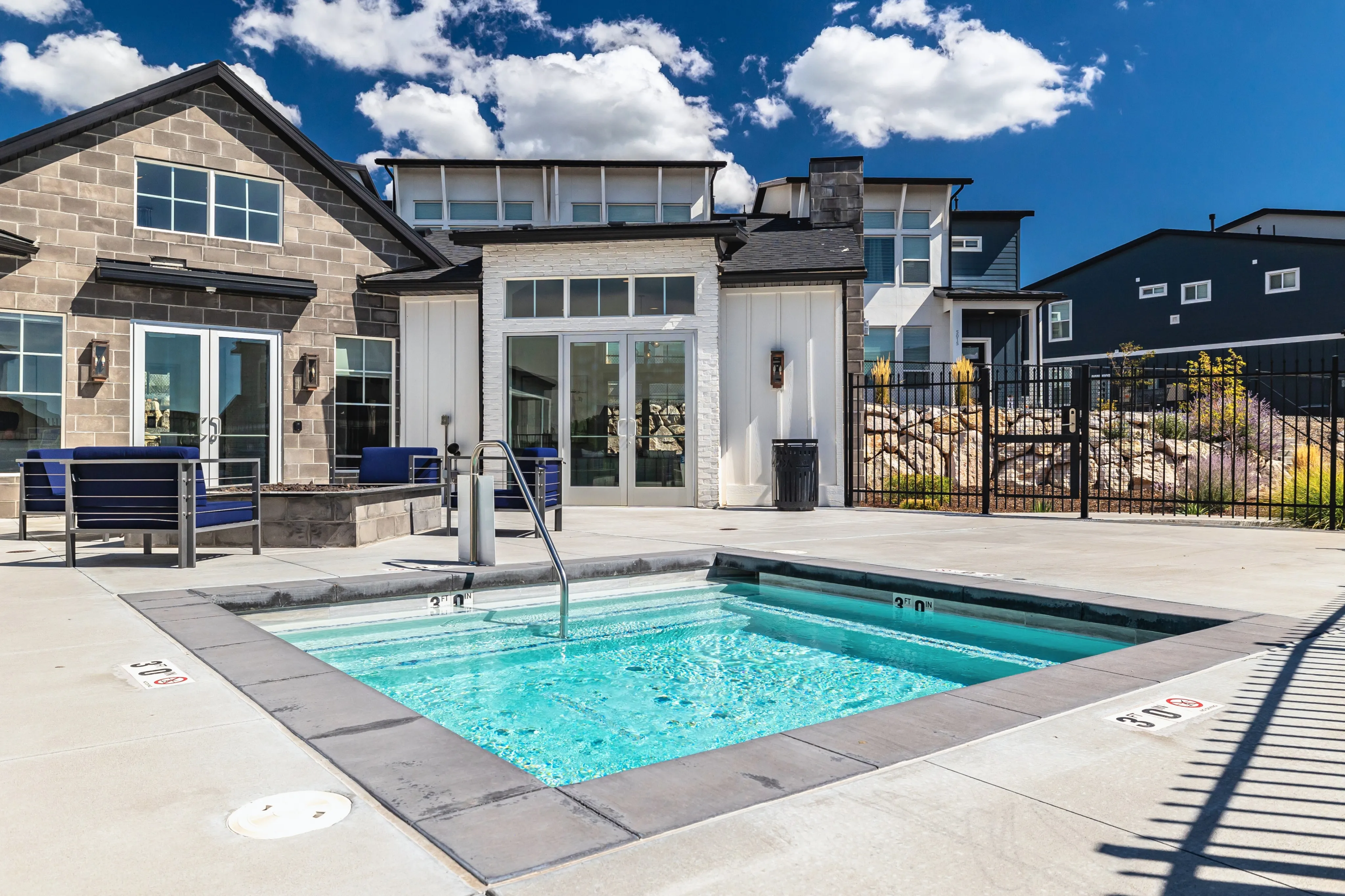 Luxurious community pool with modern seating area and stylish architecture under a clear blue sky.