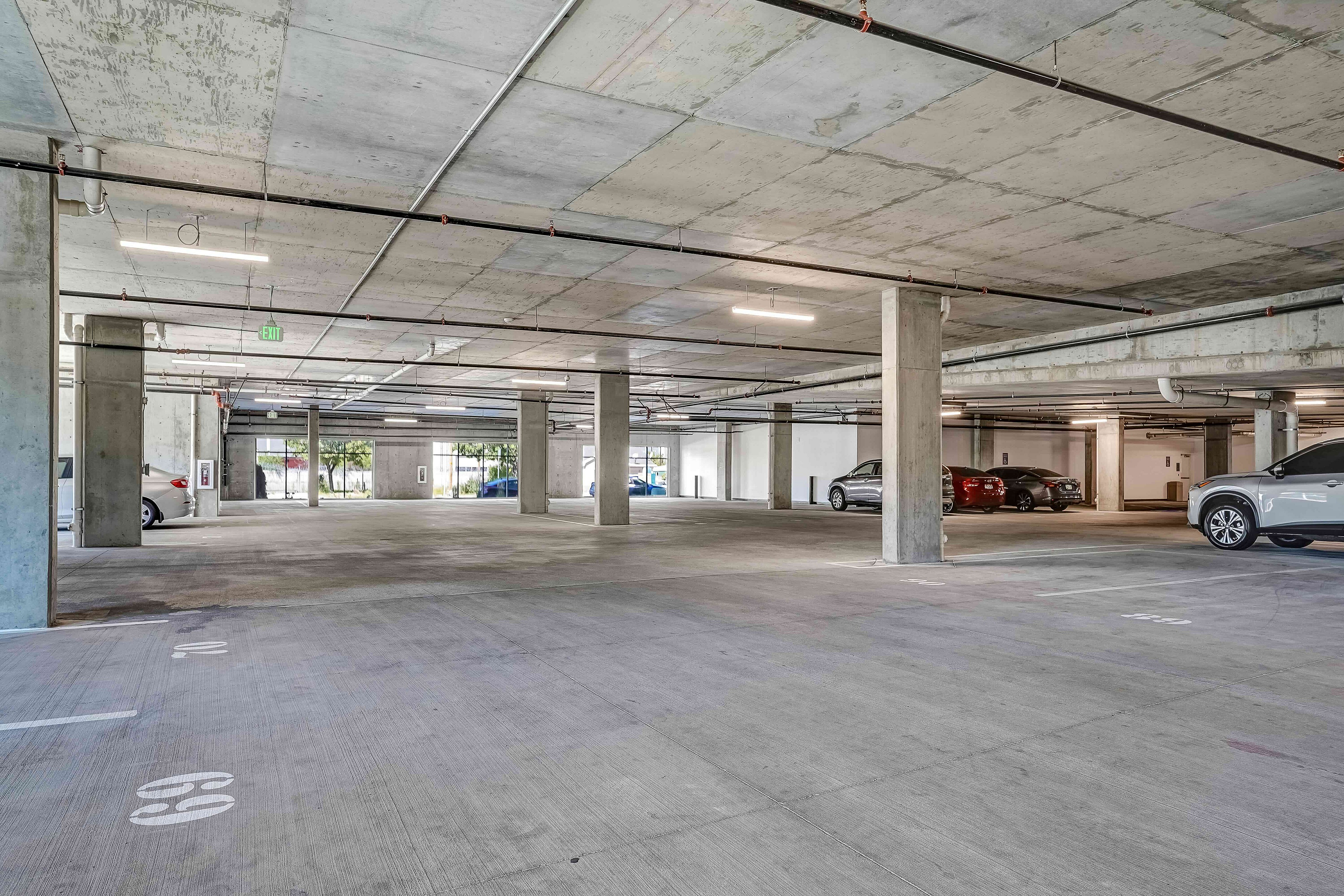 Spacious, well-lit underground parking garage with modern design and multiple parked cars.