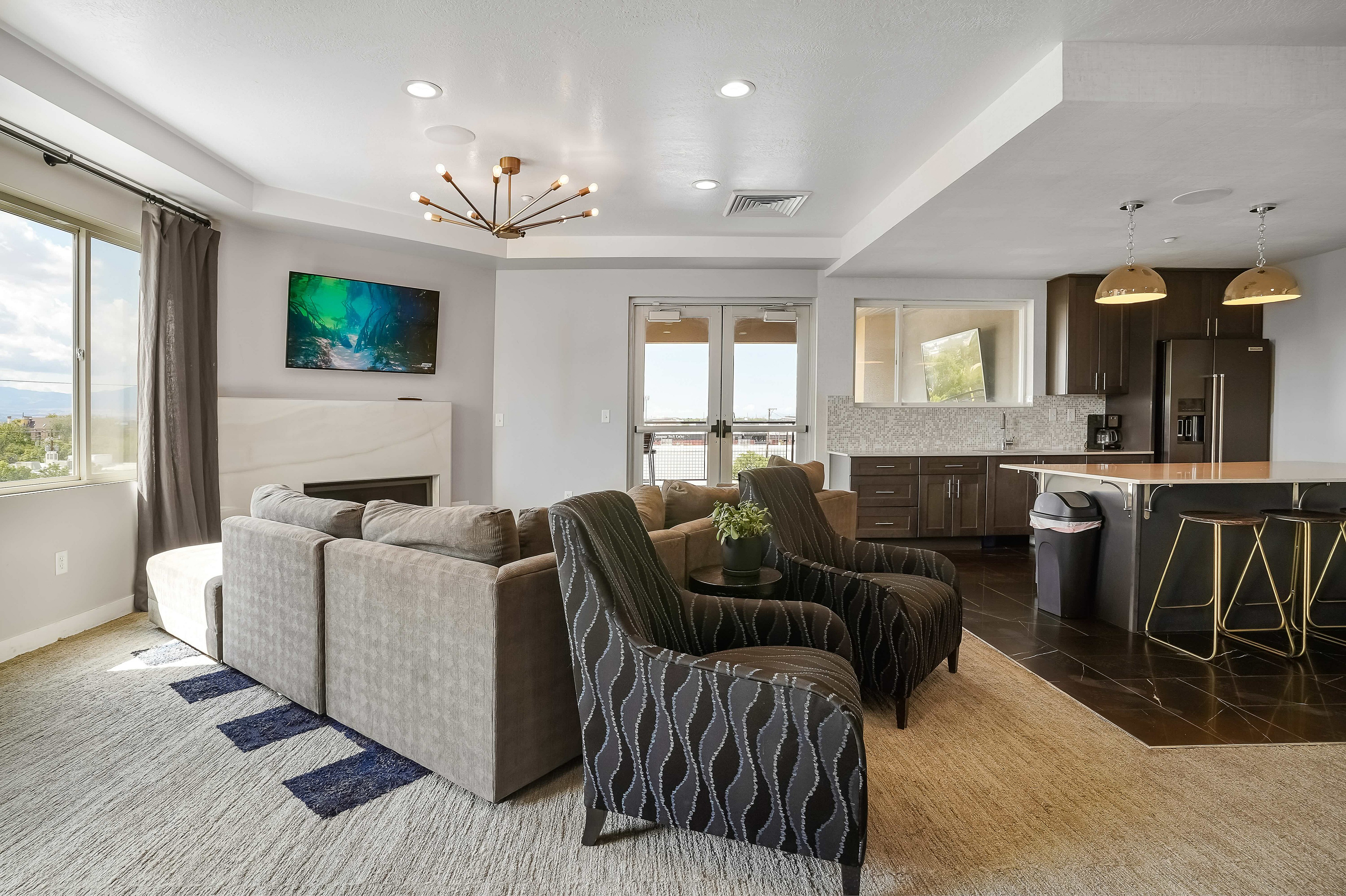 Elegant open-concept living room with modern furniture, stylish decor, and a sleek kitchen with high-end appliances.