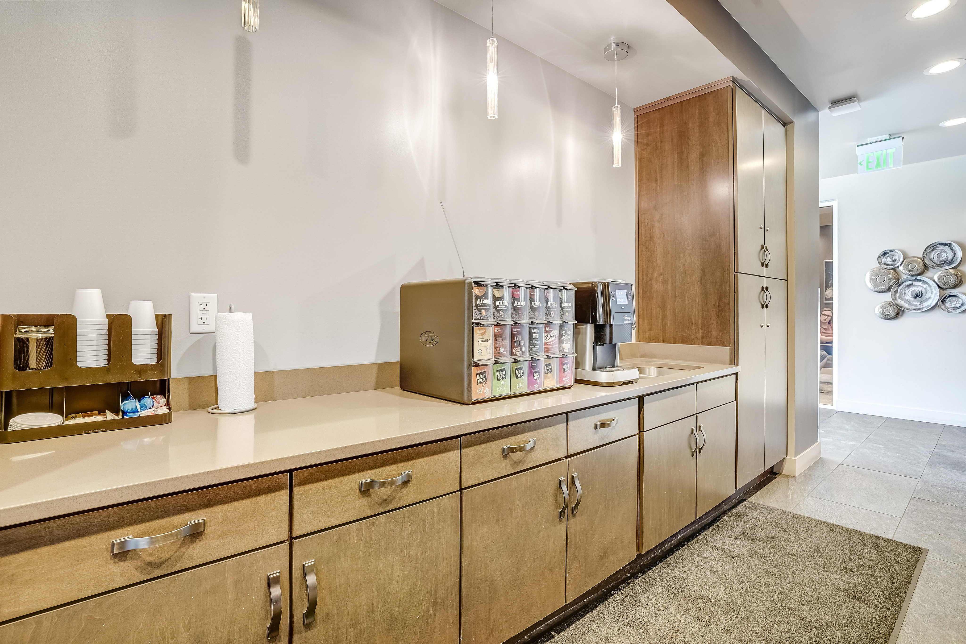 Modern kitchen station with sleek cabinetry, coffee machine, and decorative accents in a stylish apartment setting.