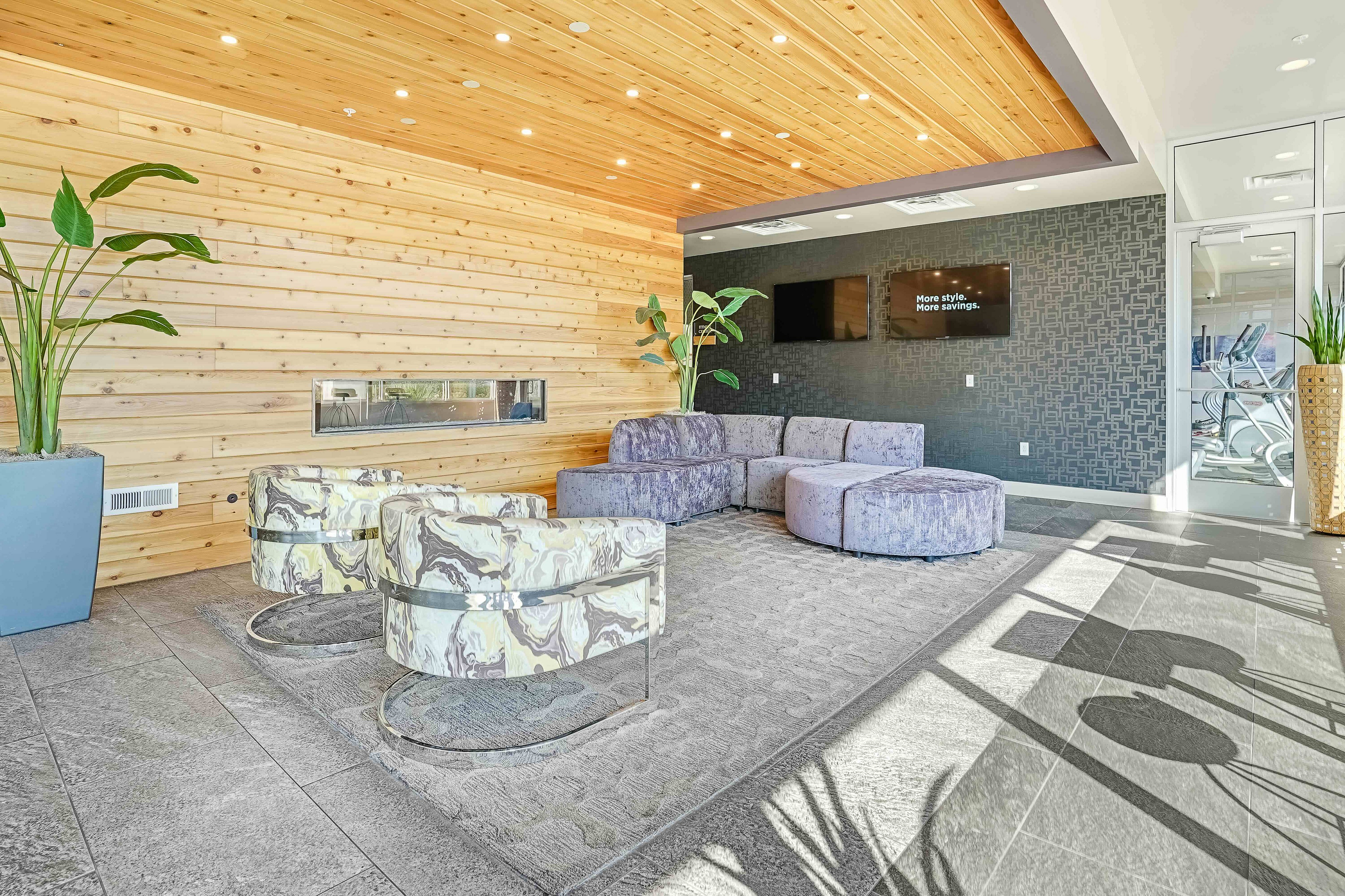 Elegant lobby showcasing a modern wooden ceiling, plush seating area, stylish armchairs, and vibrant plants, creating a welcoming atmosphere.