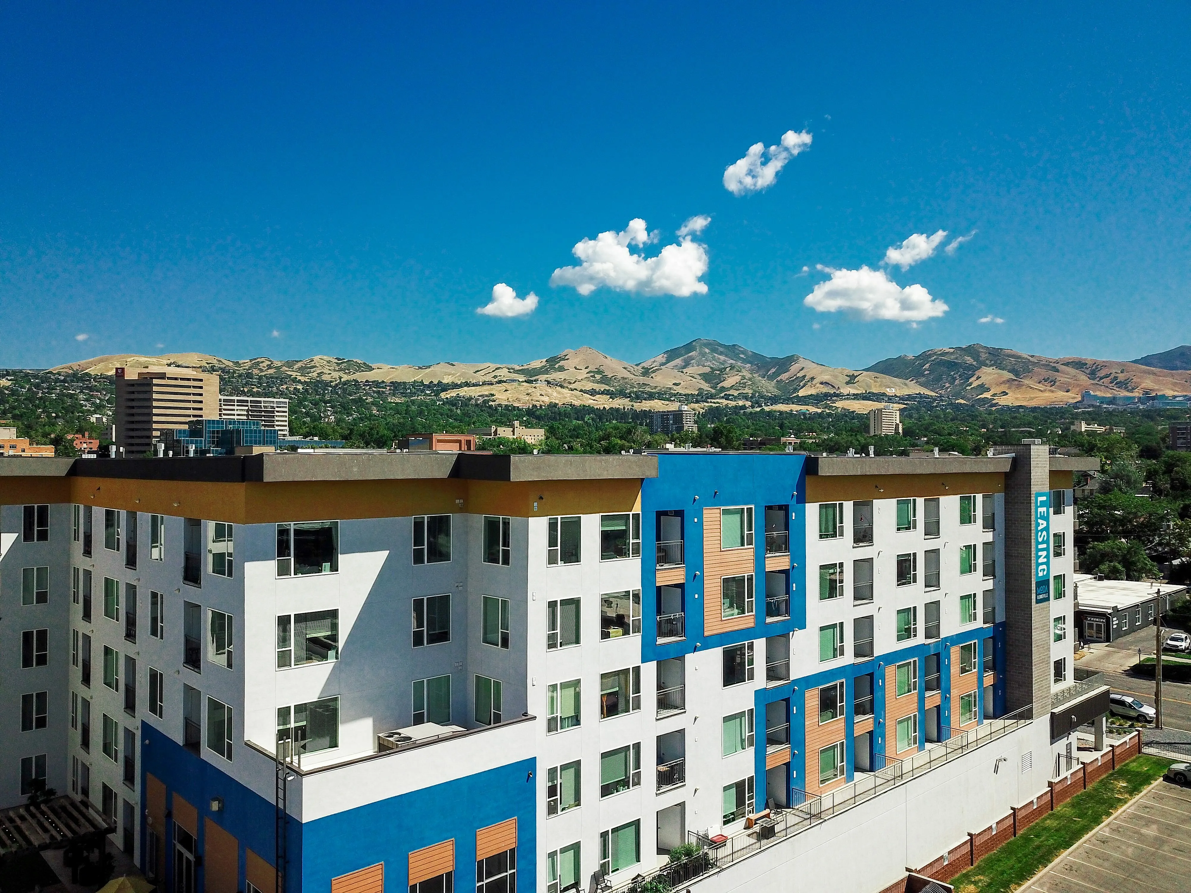Modern apartment complex with vibrant blue accents, offering stunning mountain views and ample natural light.