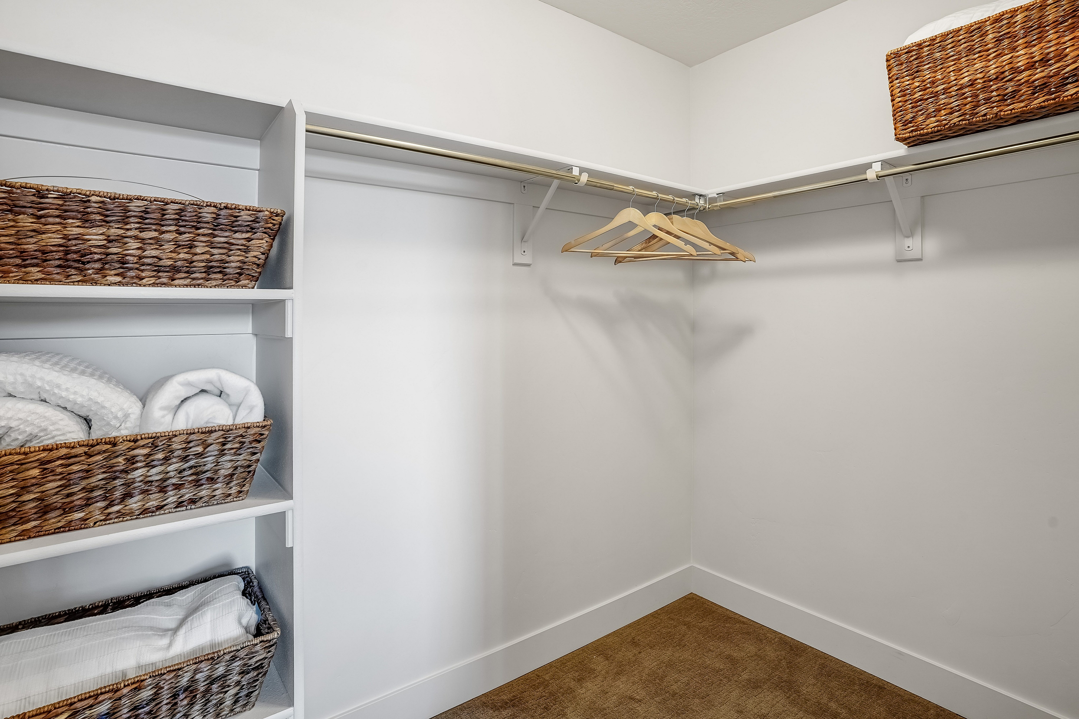 Spacious walk-in closet with custom shelving and elegant wicker baskets, perfect for organized living.