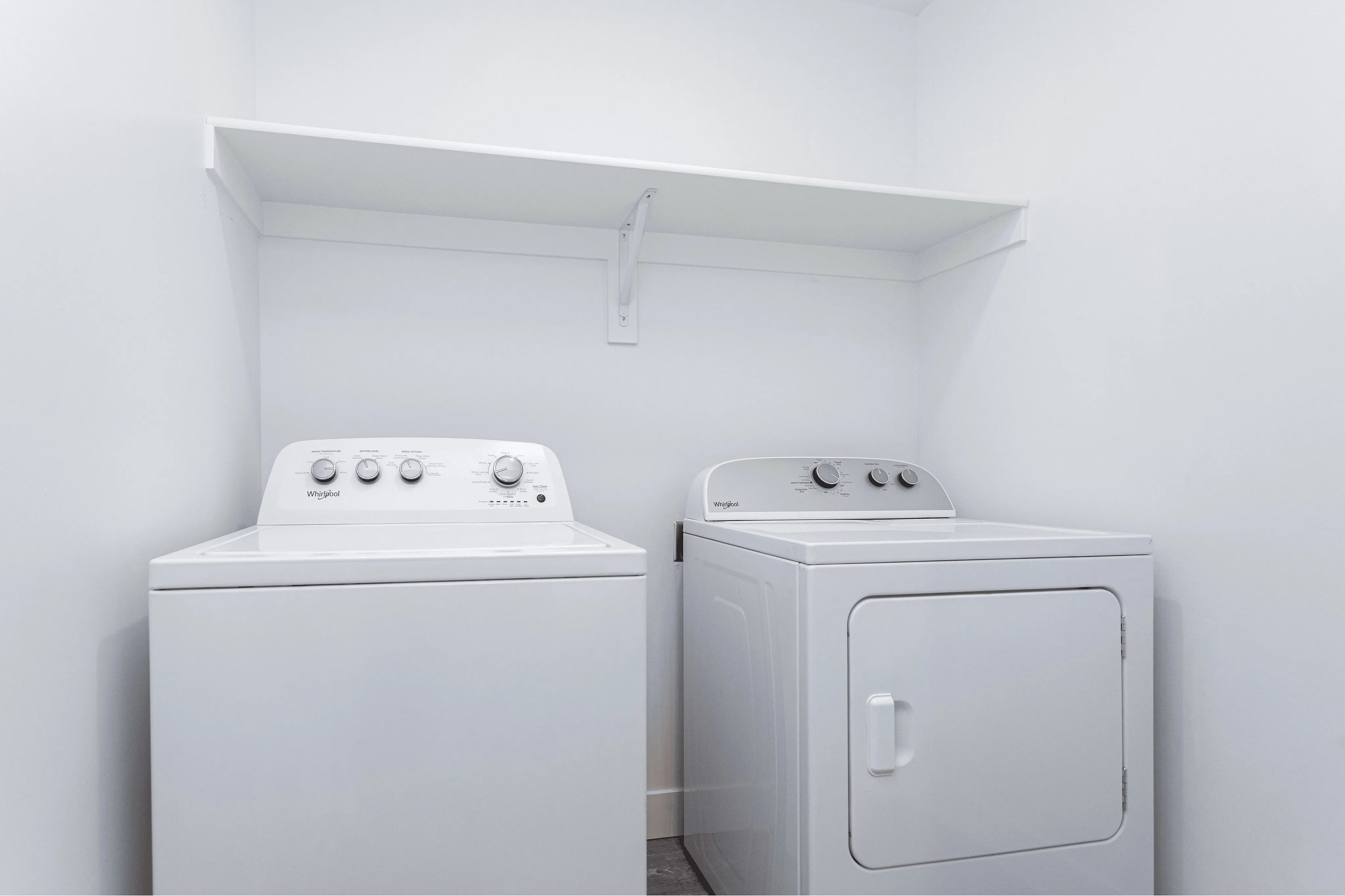 Modern laundry room with high-efficiency washer and dryer, ample shelving for storage in a bright, clean space.