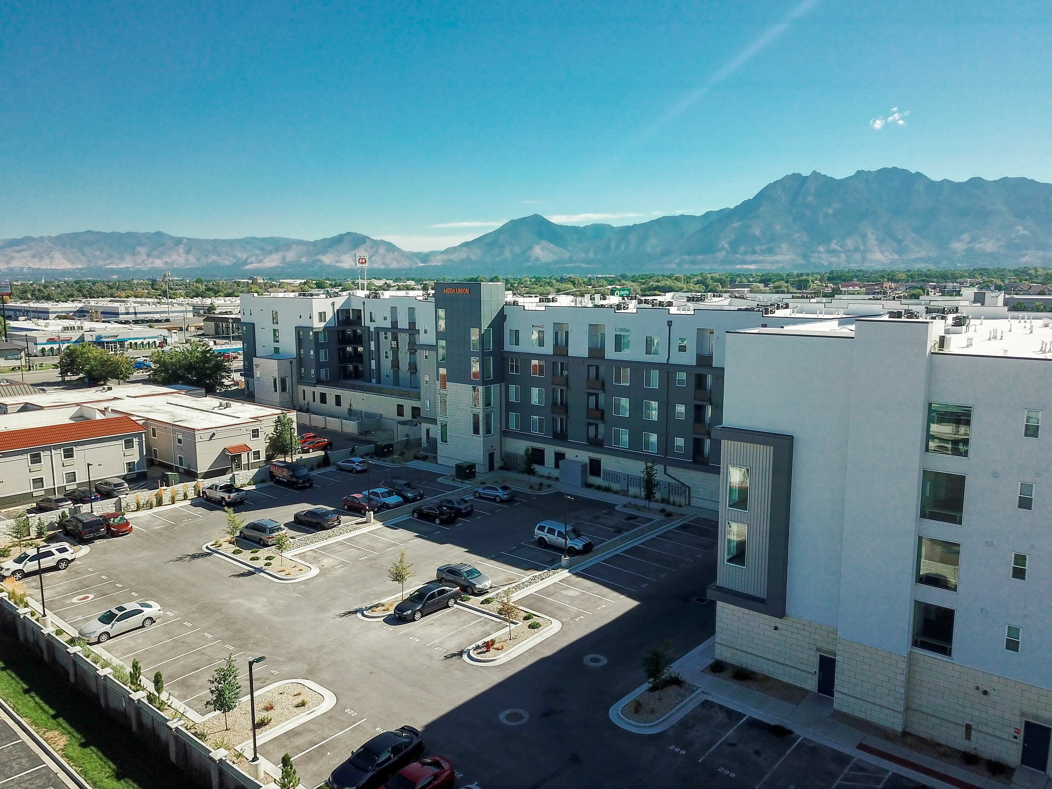 Modern apartment building with beautiful mountain views, ample parking spaces, and a vibrant community setting.