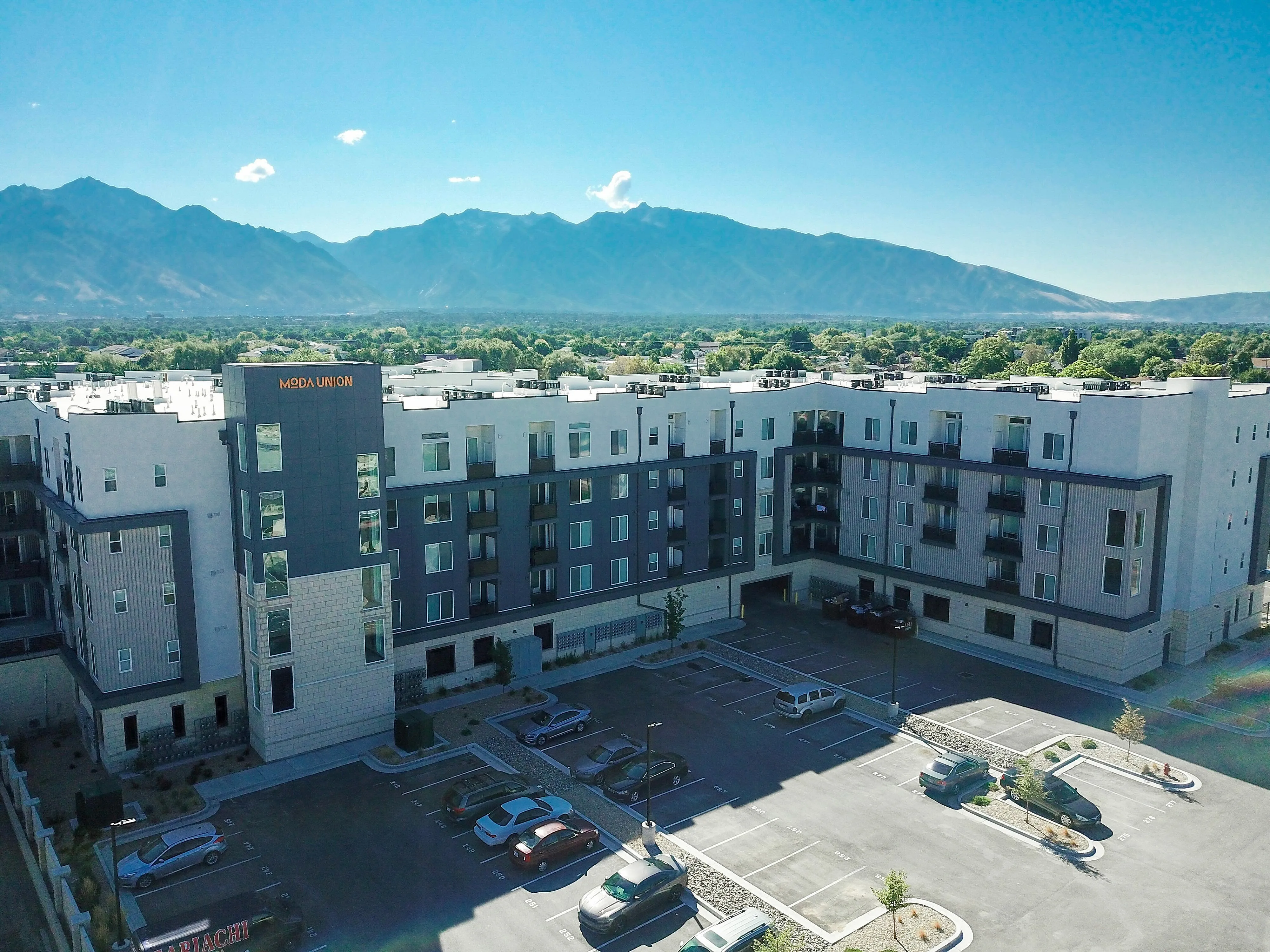 Modern apartment complex with stunning mountain views, featuring spacious balconies and ample parking facilities.