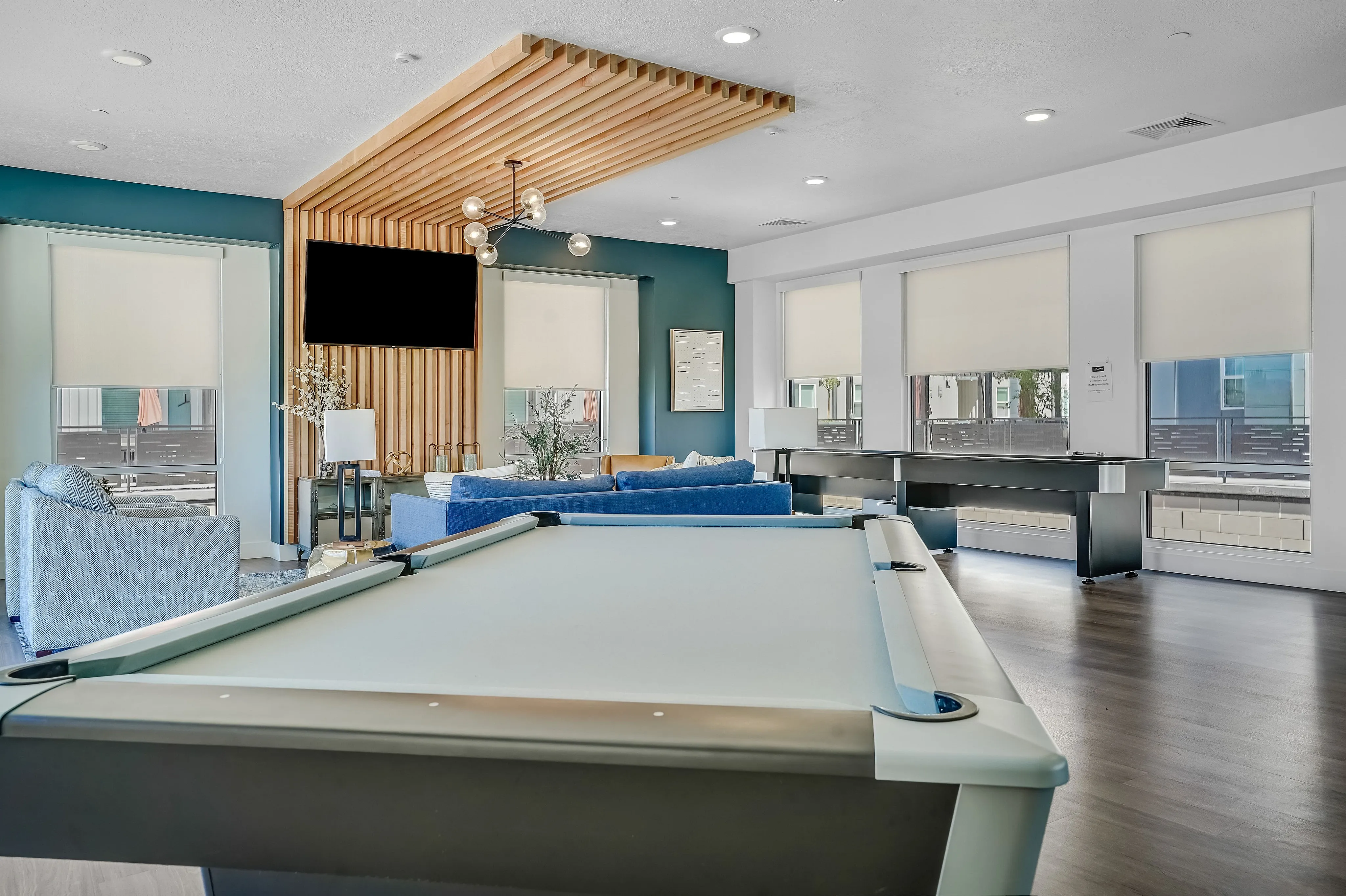 Chic communal lounge boasting a modern pool table, elegant seating, and a stylish wooden ceiling accent.