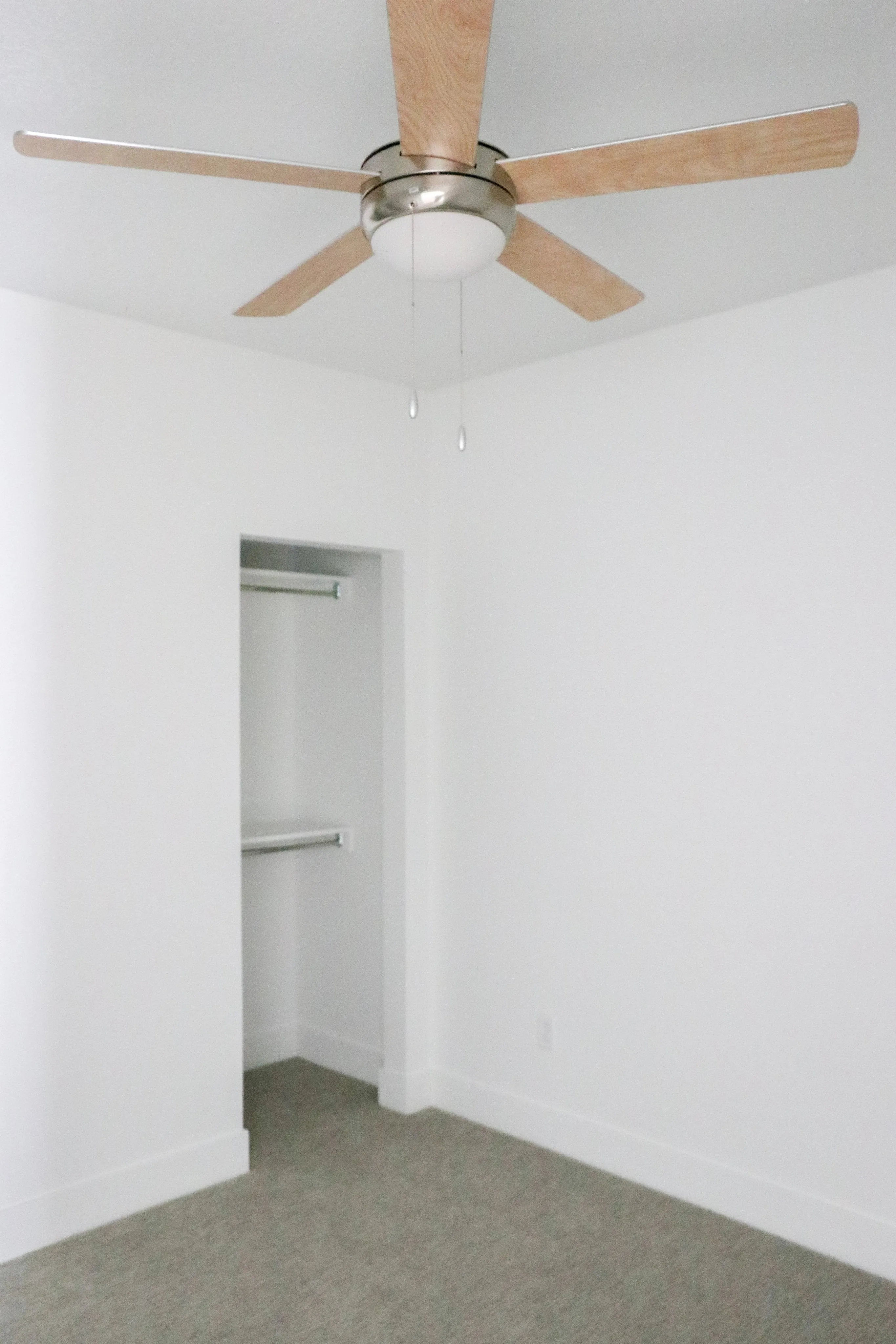 Bright and airy bedroom with sleek ceiling fan and spacious closet, perfect for modern living.