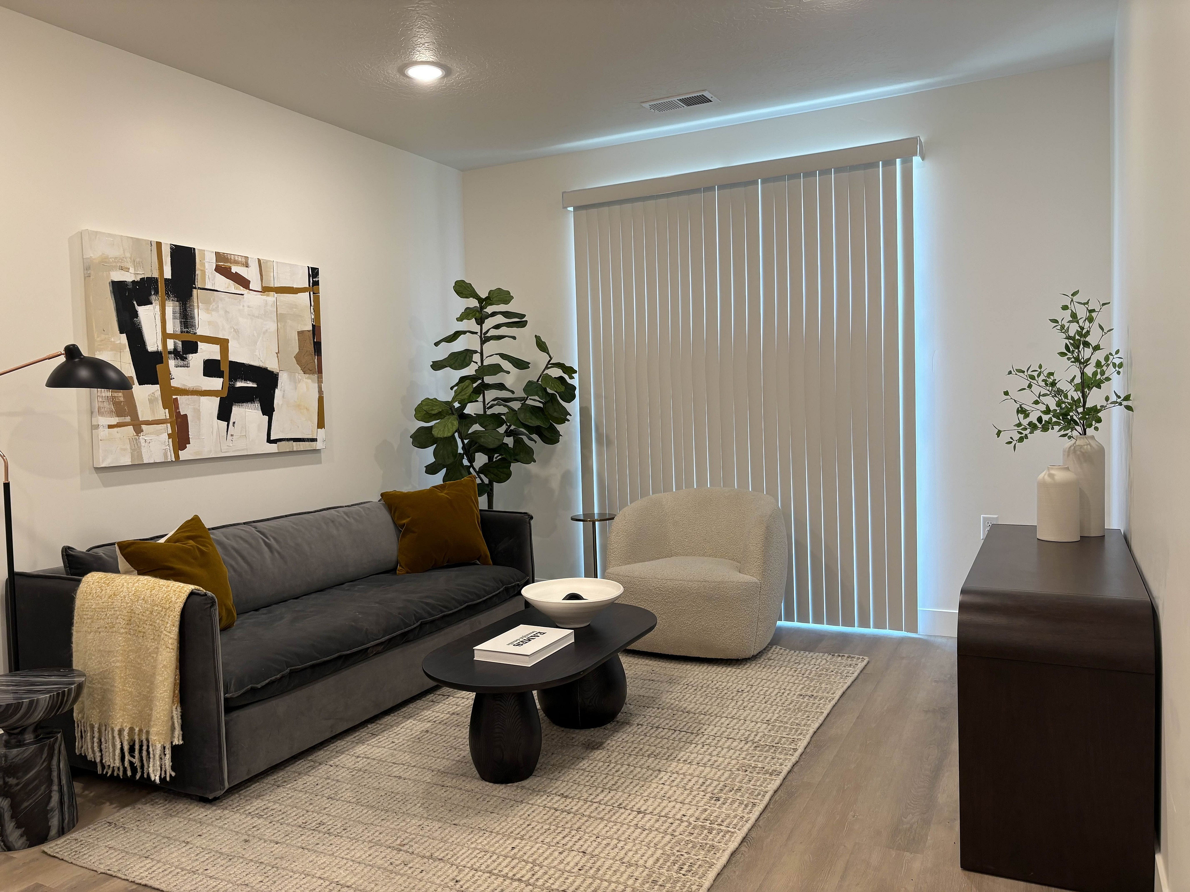 Contemporary living room featuring a sleek gray sofa, stylish abstract artwork, and cozy lighting, perfect for relaxation.