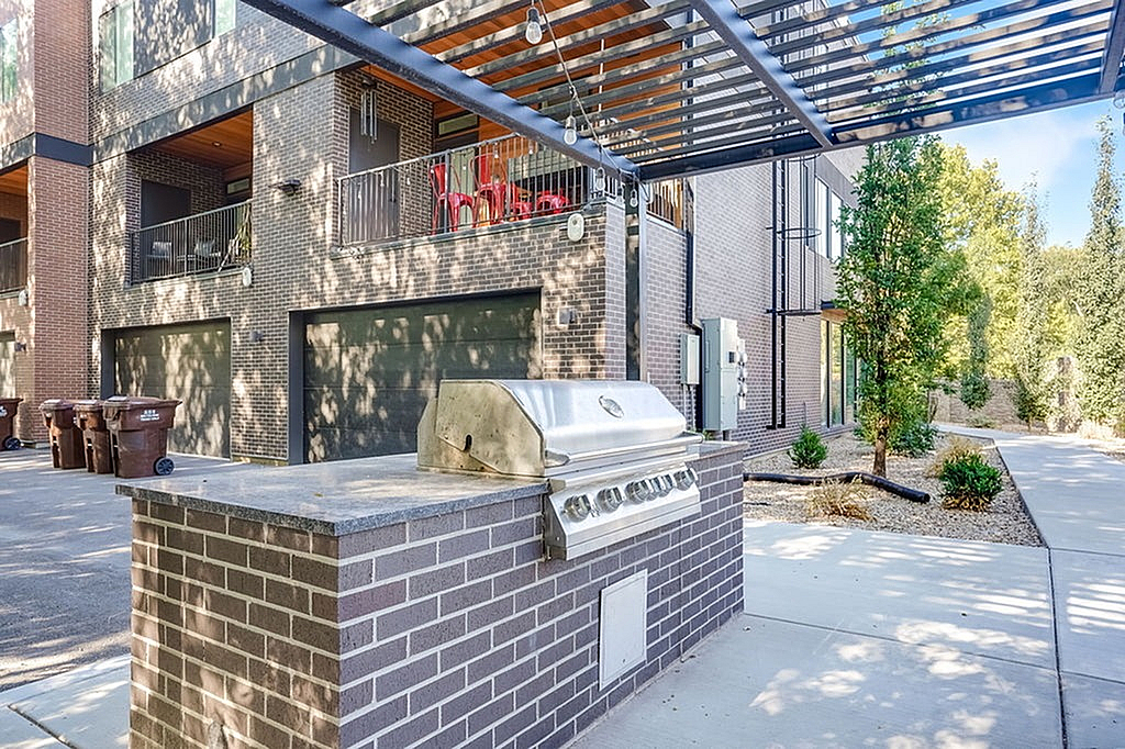 Modern urban apartment exterior with stylish brick design and equipped with a sleek outdoor BBQ area under pergola, perfect for entertaining.