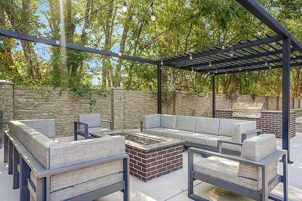Chic outdoor patio with cozy seating, pergola, and modern fire pit, perfect for entertaining.