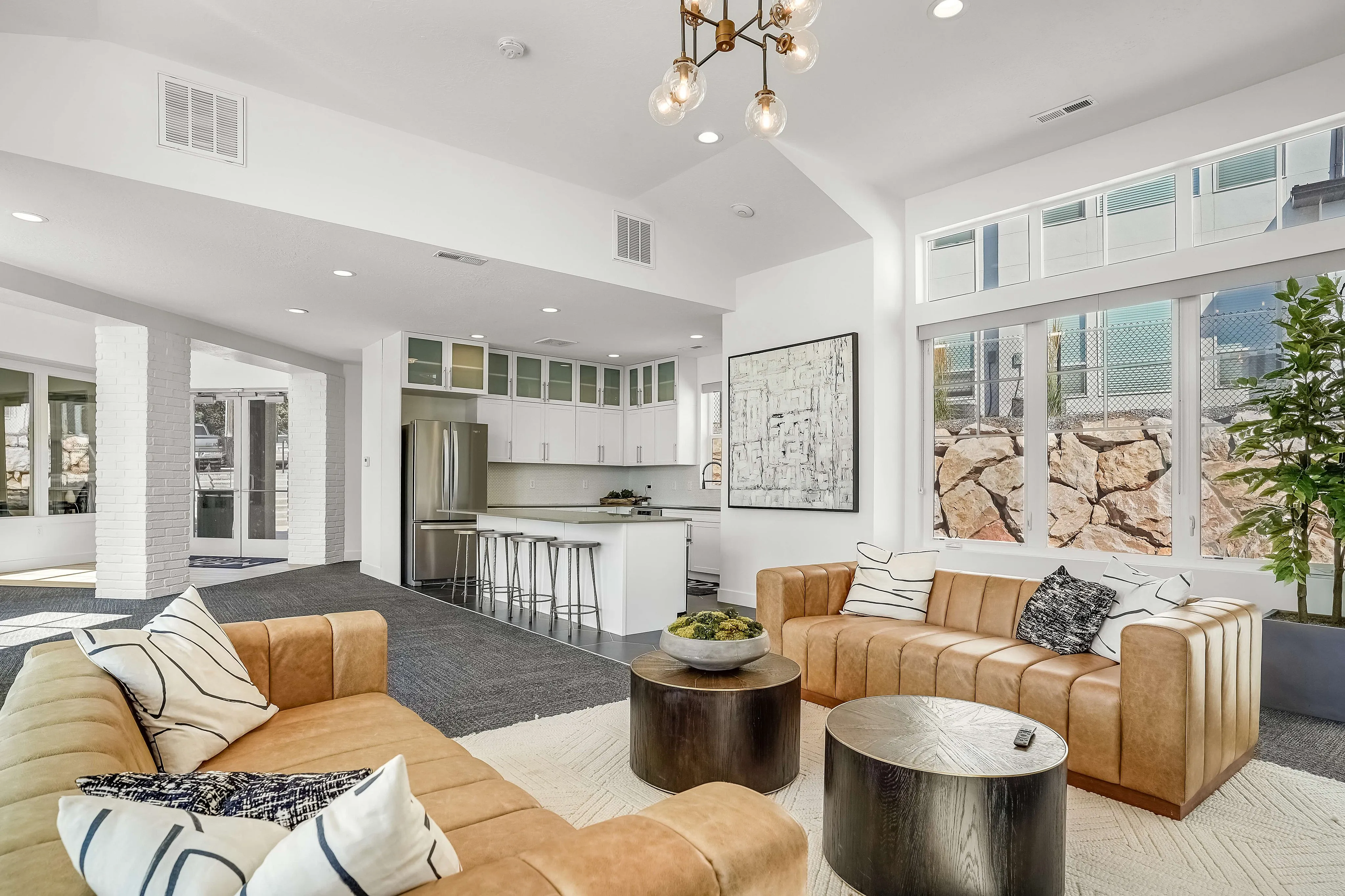 Modern living area with sleek kitchen, comfortable leather sofas, stylish decor, and abundant natural light.