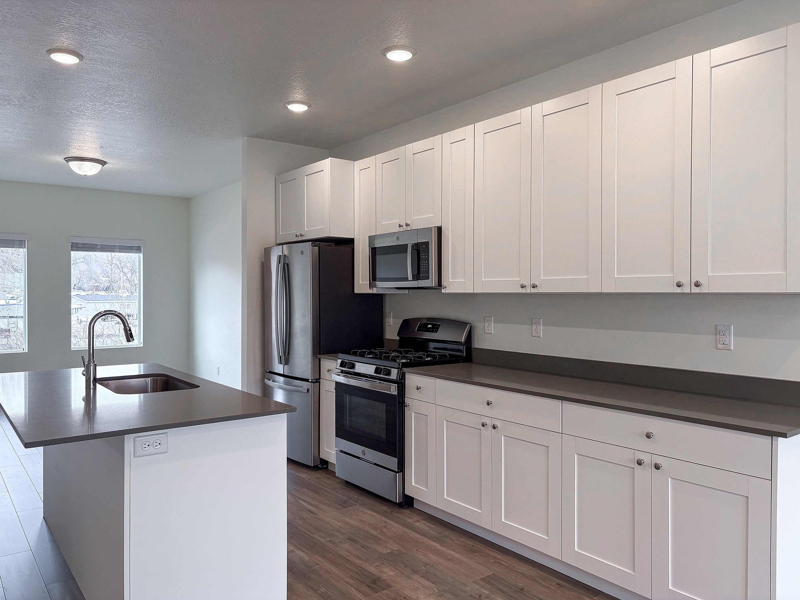 Sleek modern kitchen featuring stainless steel appliances, elegant white cabinetry, and a spacious island with built-in sink.