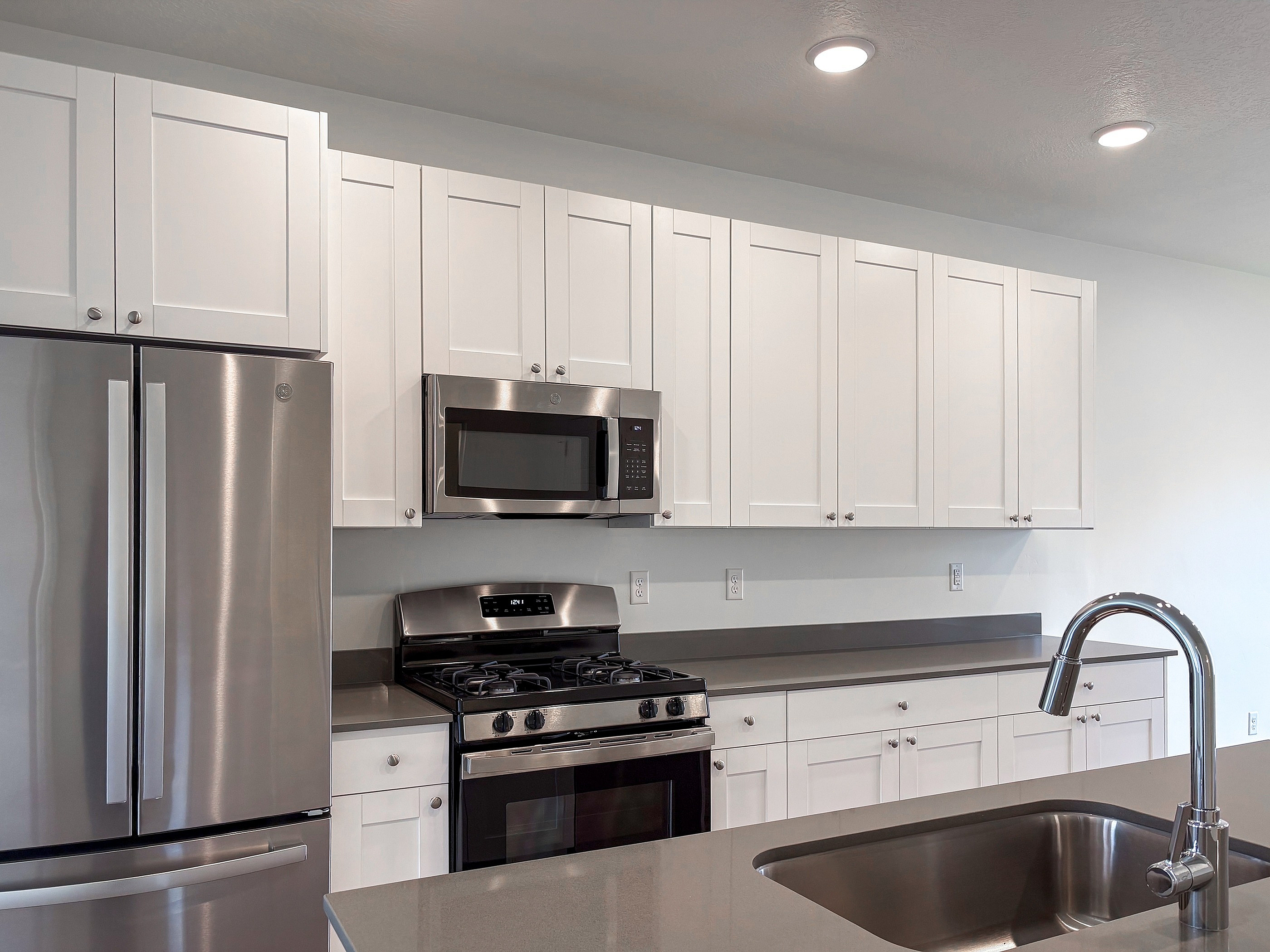 Modern kitchen with sleek stainless steel appliances, white cabinetry, and a stylish island with a built-in sink.