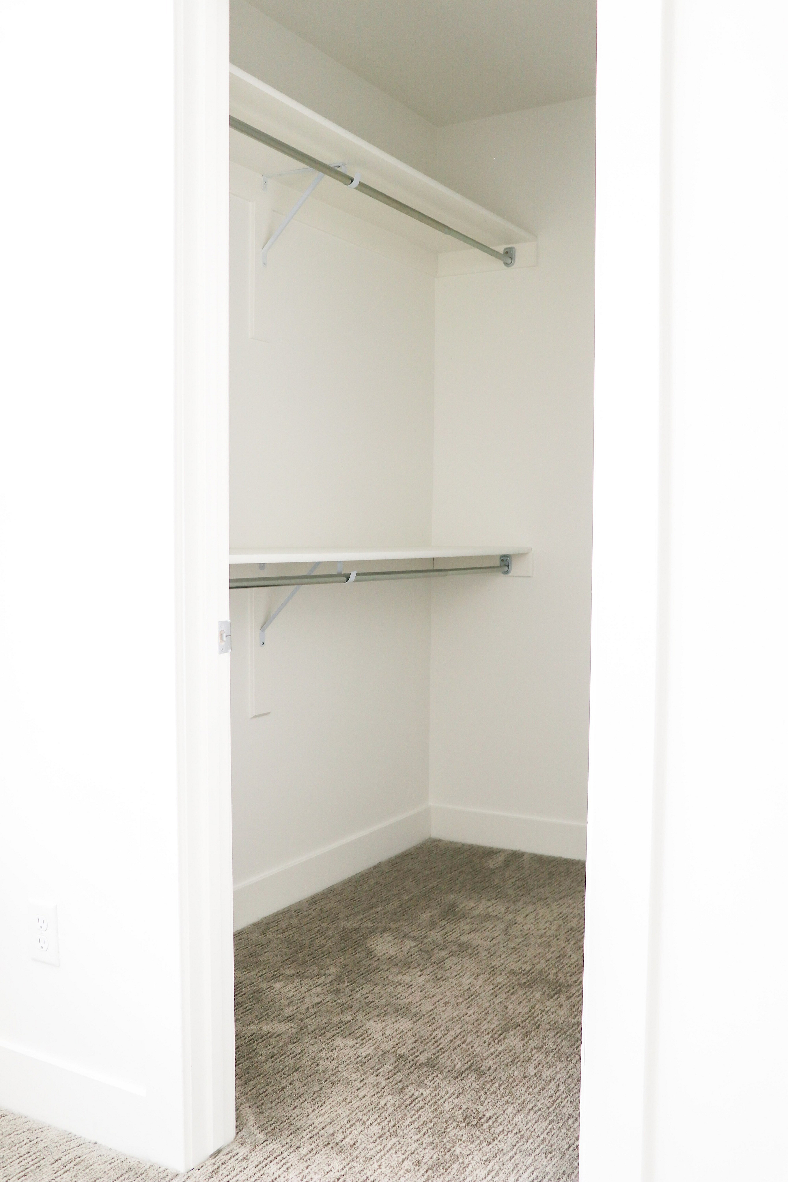 Spacious walk-in closet with built-in shelving and plush carpeting, perfect for organized storage.