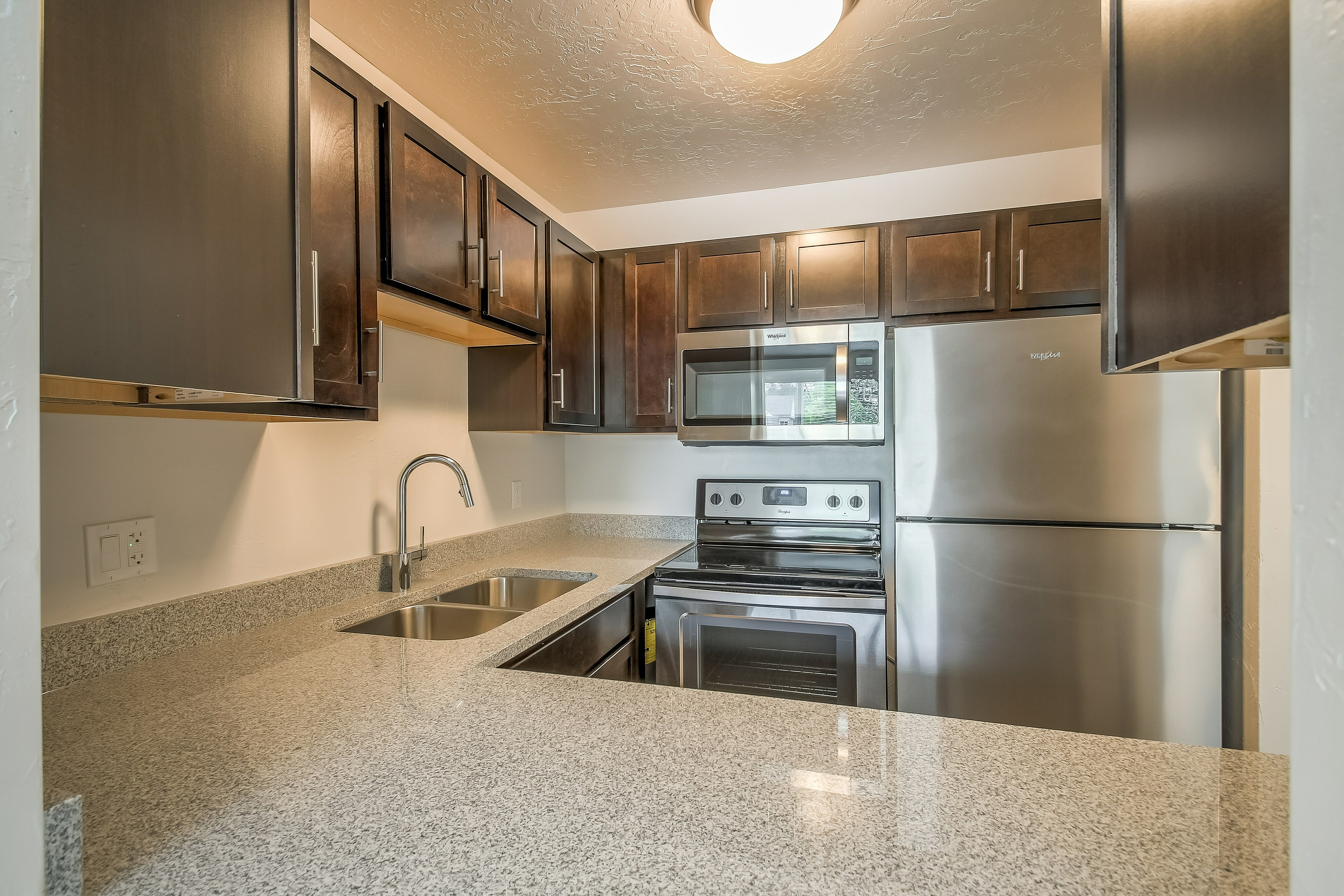 Modern kitchen with sleek dark wood cabinets, stainless steel appliances, and luxurious granite countertops.