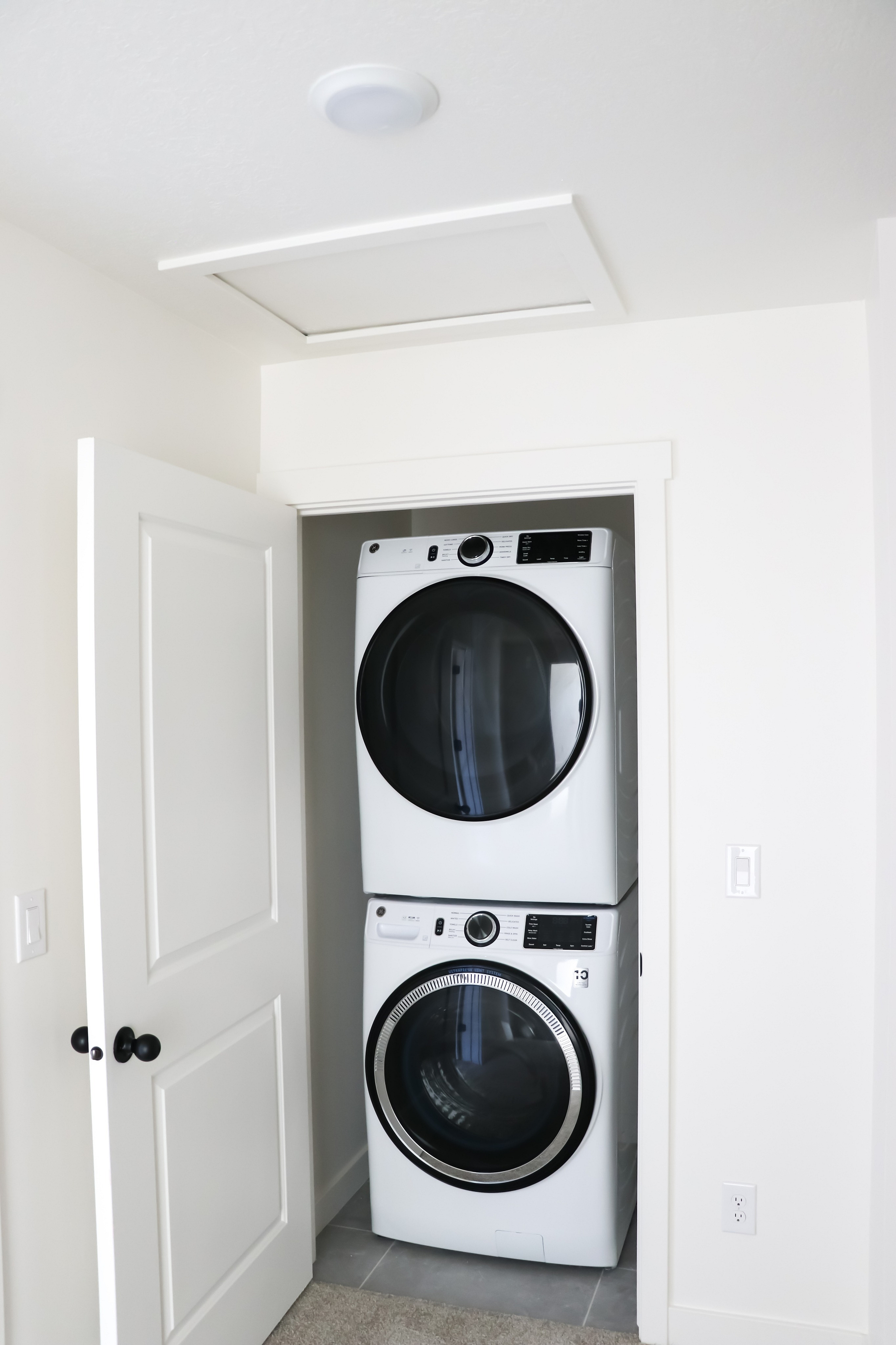 Modern apartment laundry area featuring a sleek, stacked washer and dryer set in a compact, well-designed closet space.