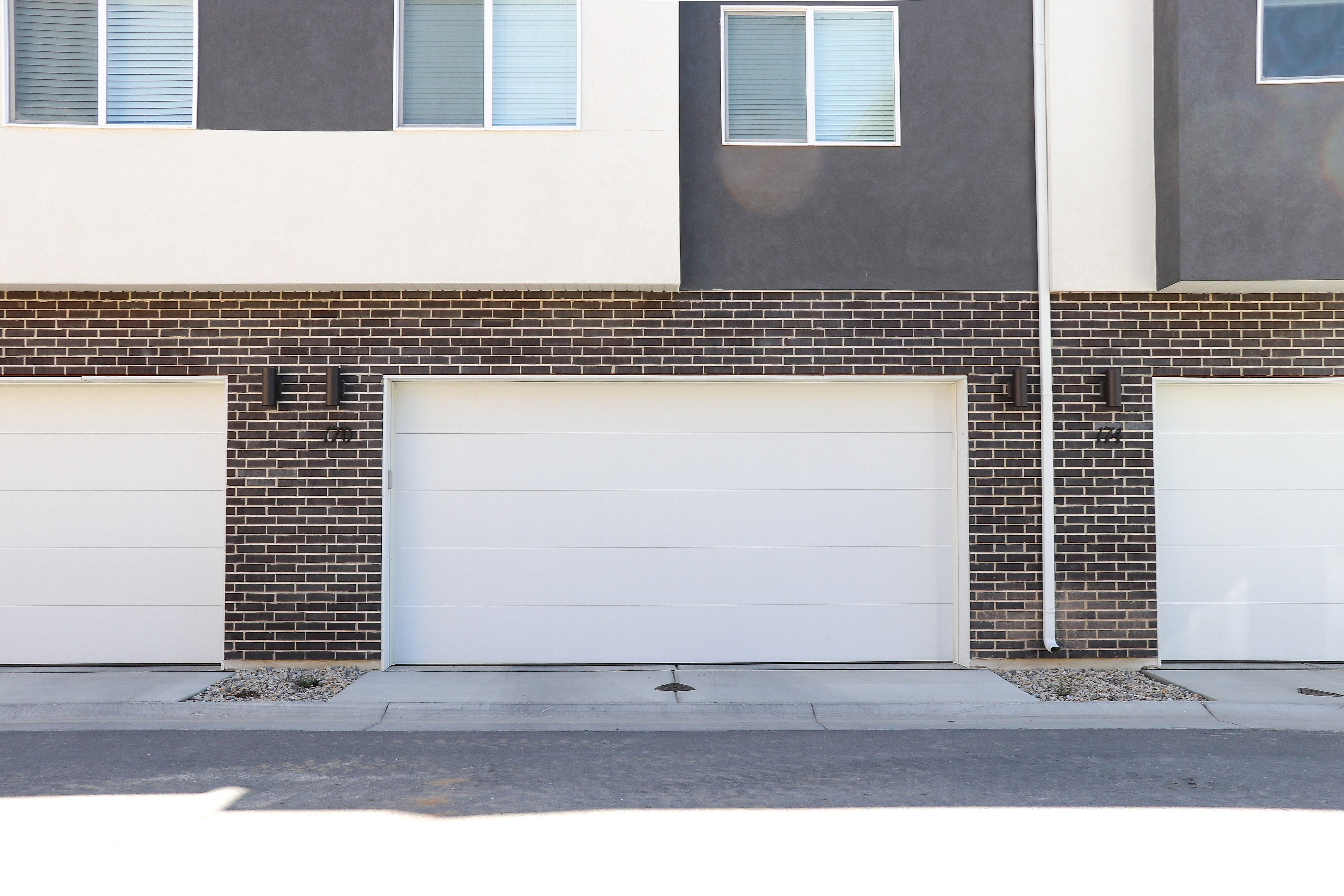 Modern townhouse exterior showcasing stylish brickwork and sleek double garage doors.