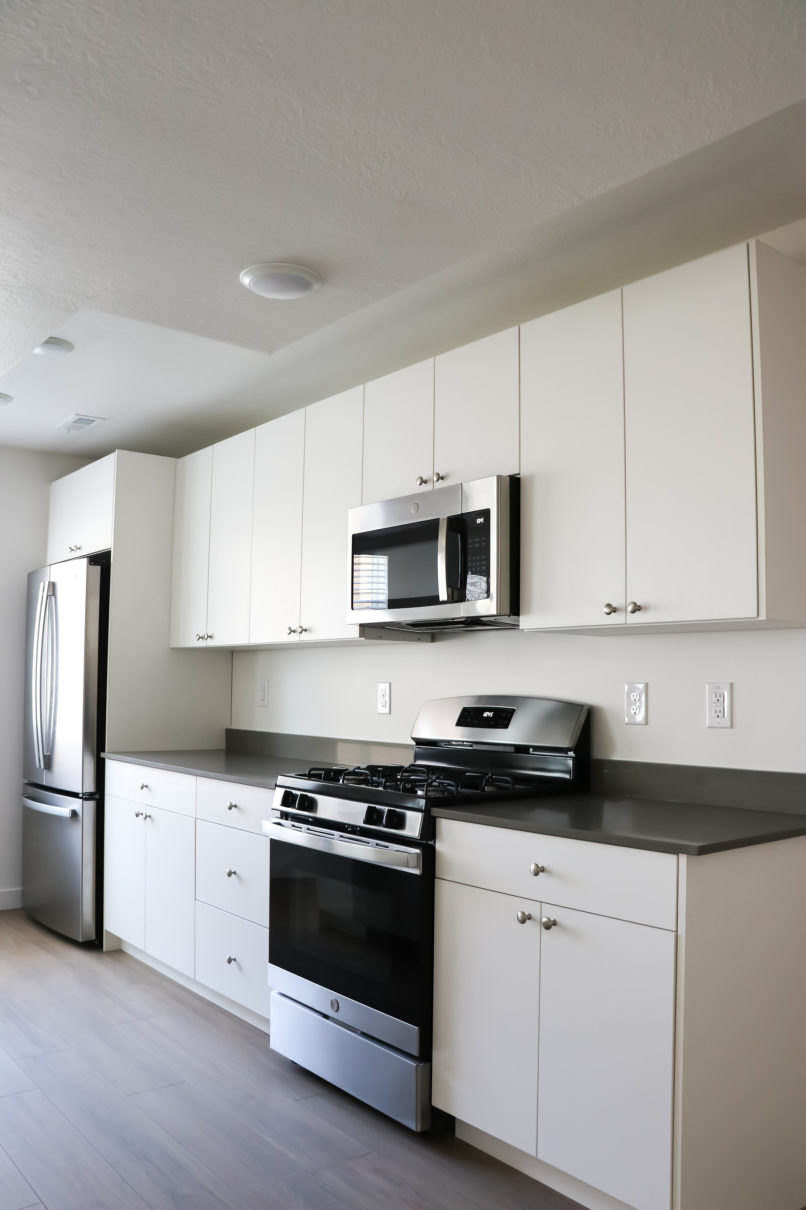 Modern kitchen with sleek stainless steel appliances, white cabinetry, and a polished countertop.