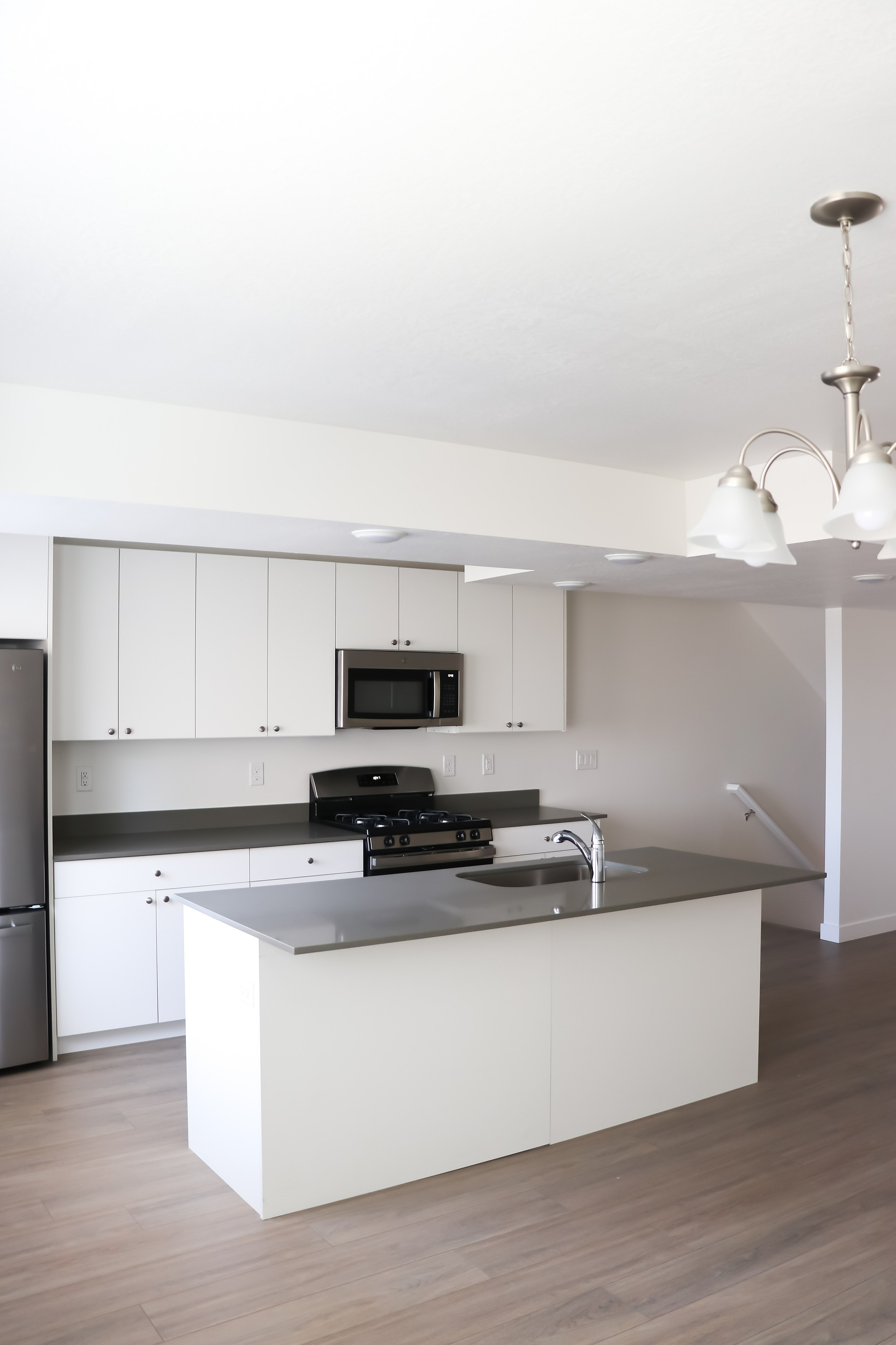 Modern kitchen with sleek white cabinets, stainless steel appliances, and elegant lighting.