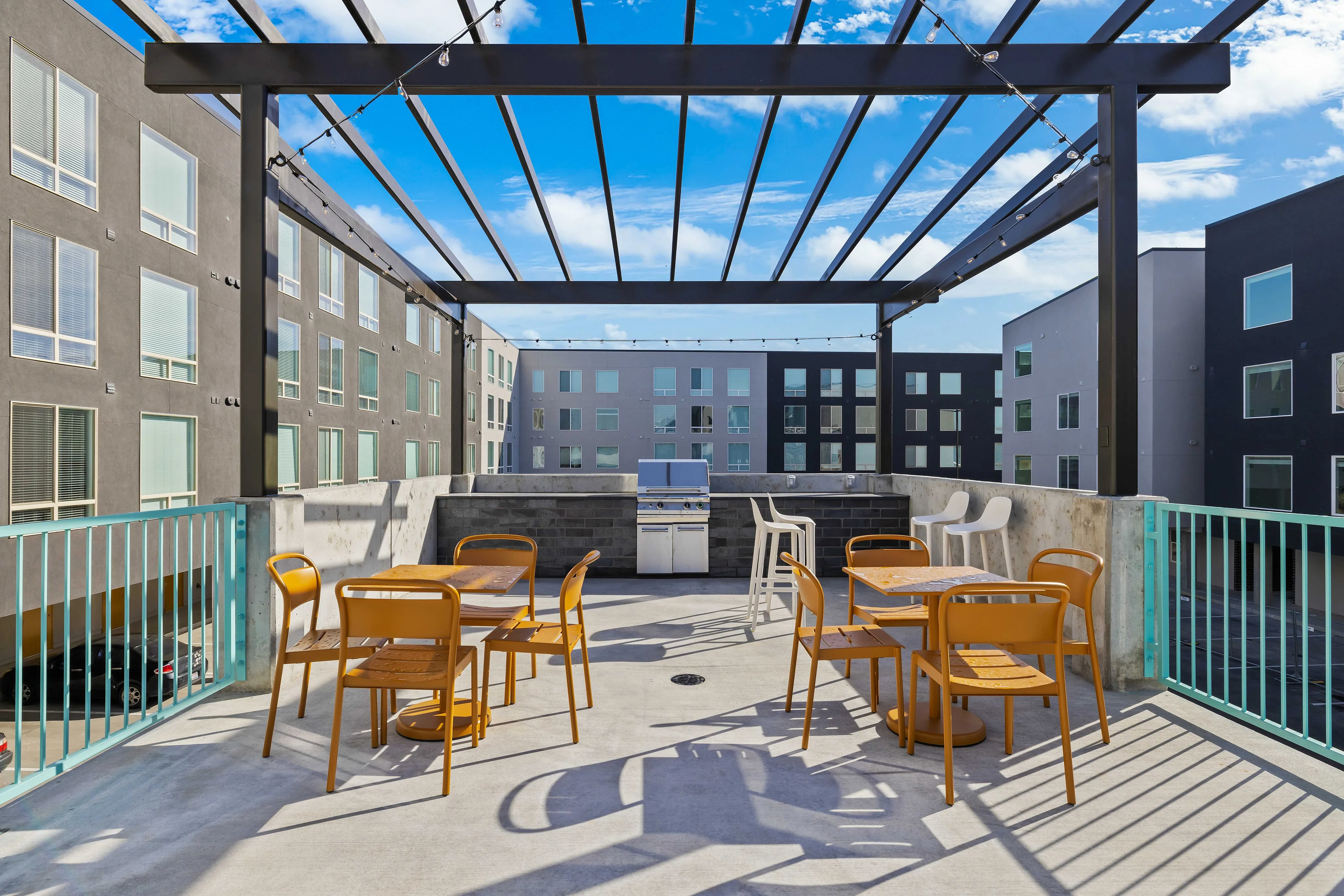 Chic modern rooftop patio with stylish seating, pergola, and barbecue area, framed by a stunning cityscape.