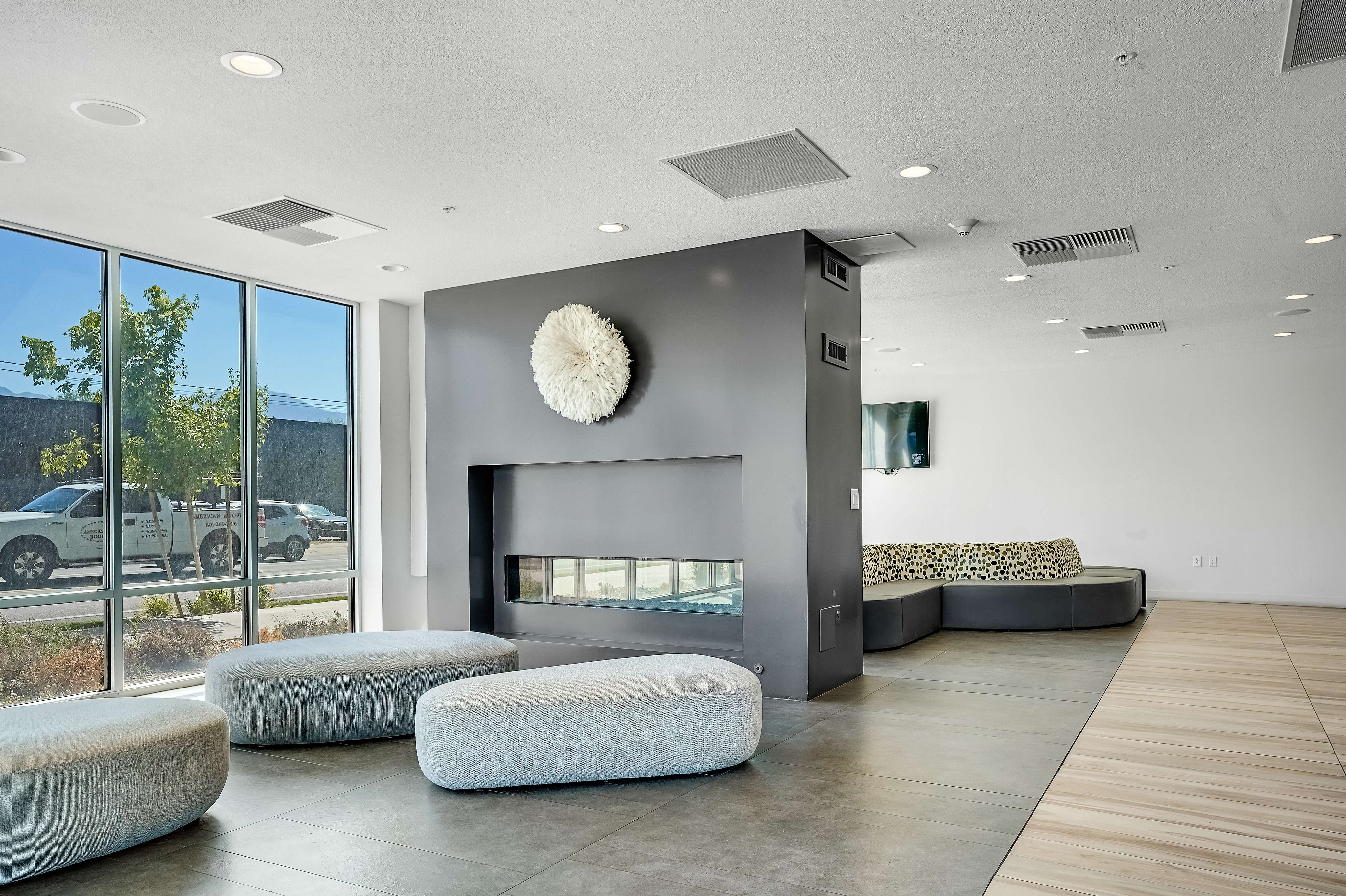 Chic modern living area with large windows, stylish seating, and a sleek fireplace, perfect for a bright and welcoming atmosphere.