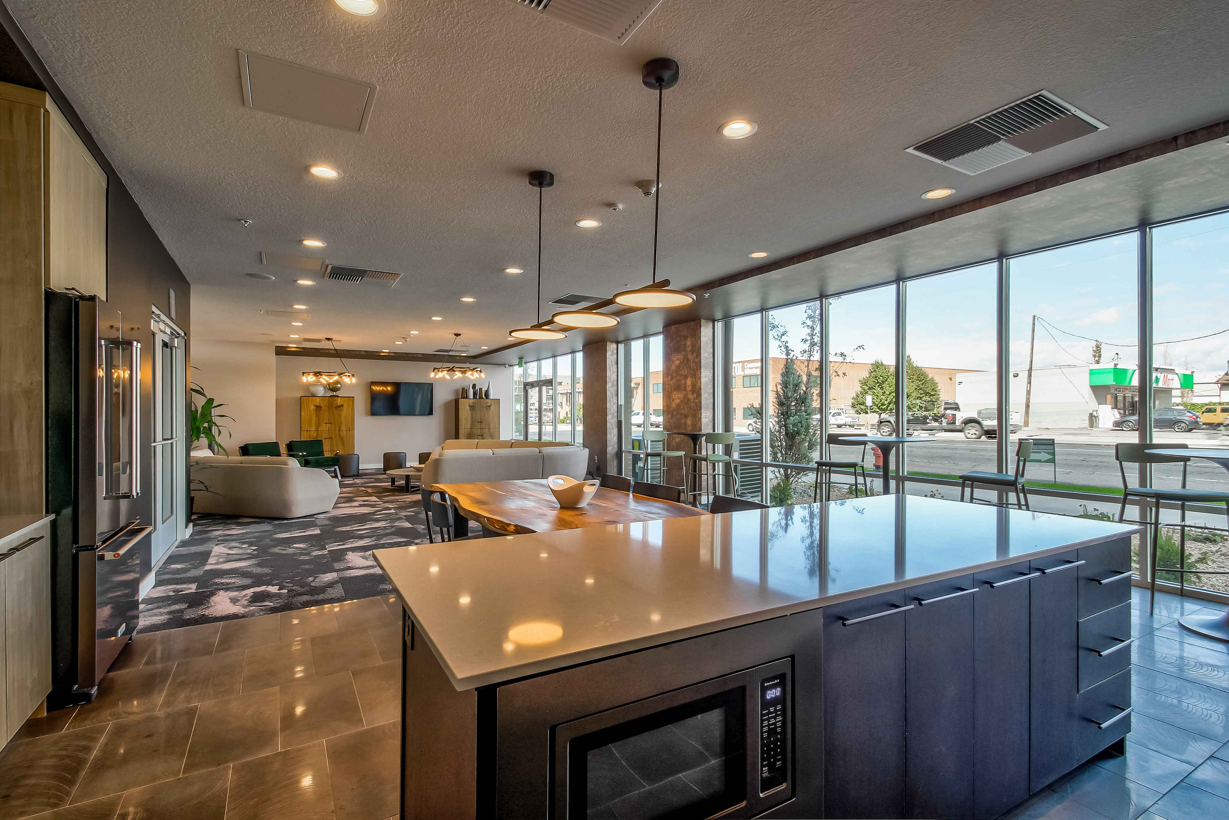 Modern open-concept space featuring a sleek kitchen island, elegant lighting, cozy seating area, and expansive windows with urban views.