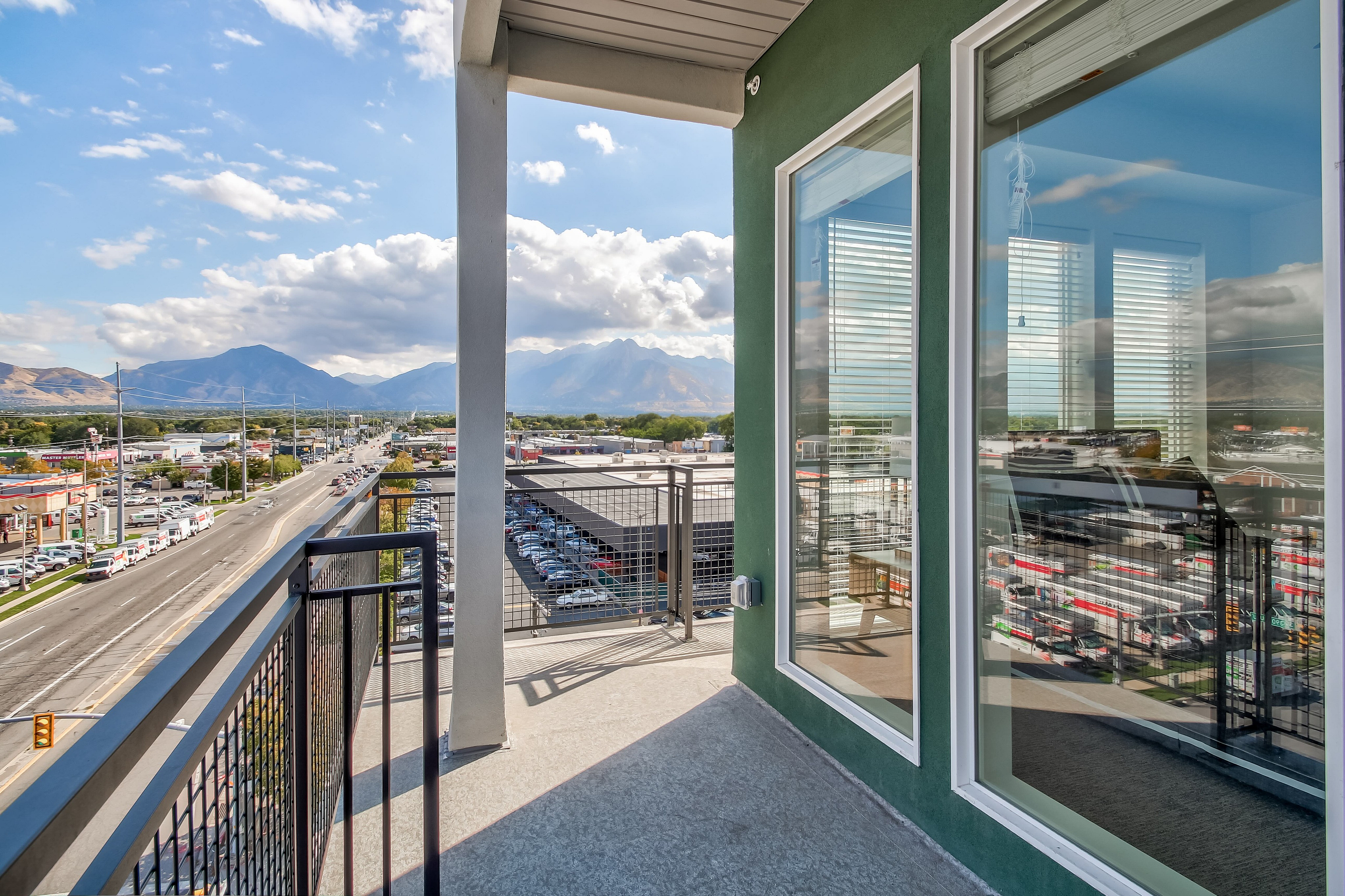 Charming apartment balcony with breathtaking mountain views and bustling cityscape, perfect for relaxation and enjoying nature\'s beauty.