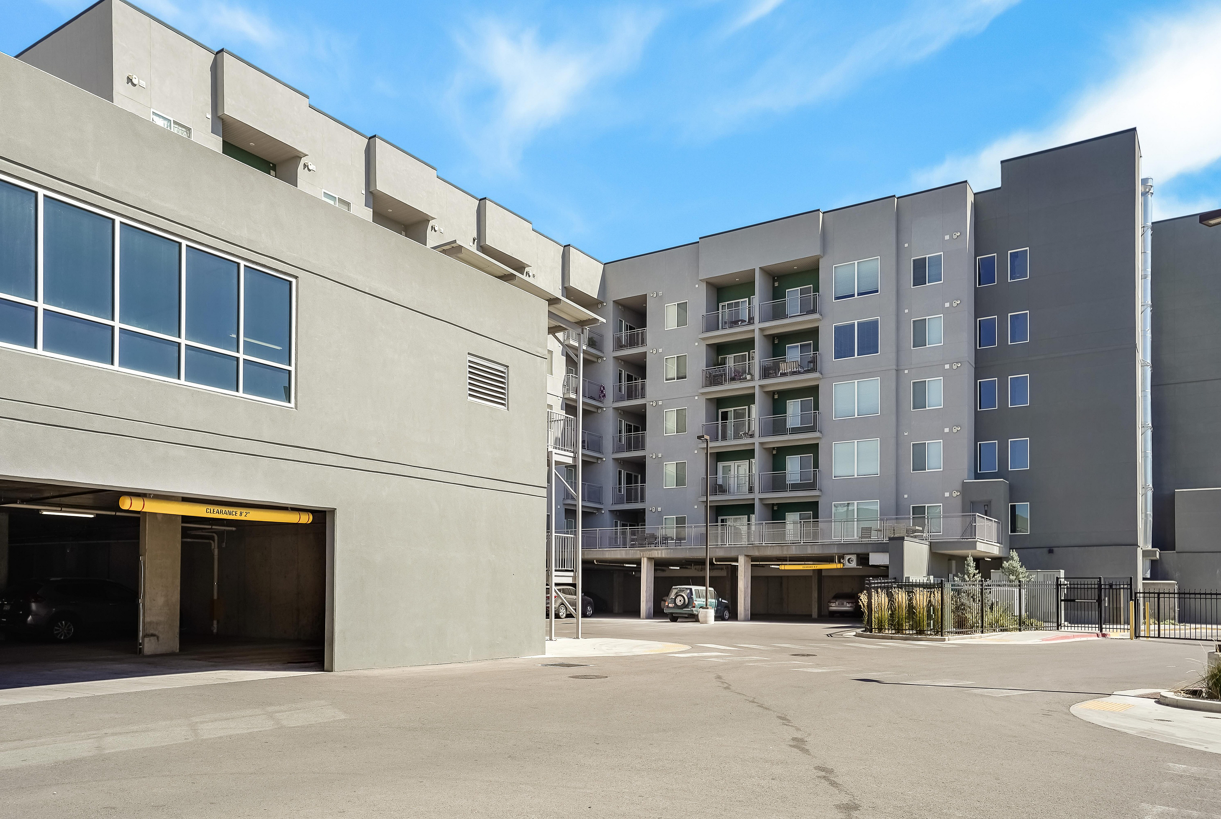 Modern apartment complex with sleek architecture, spacious balconies, and convenient parking access on a sunny day.
