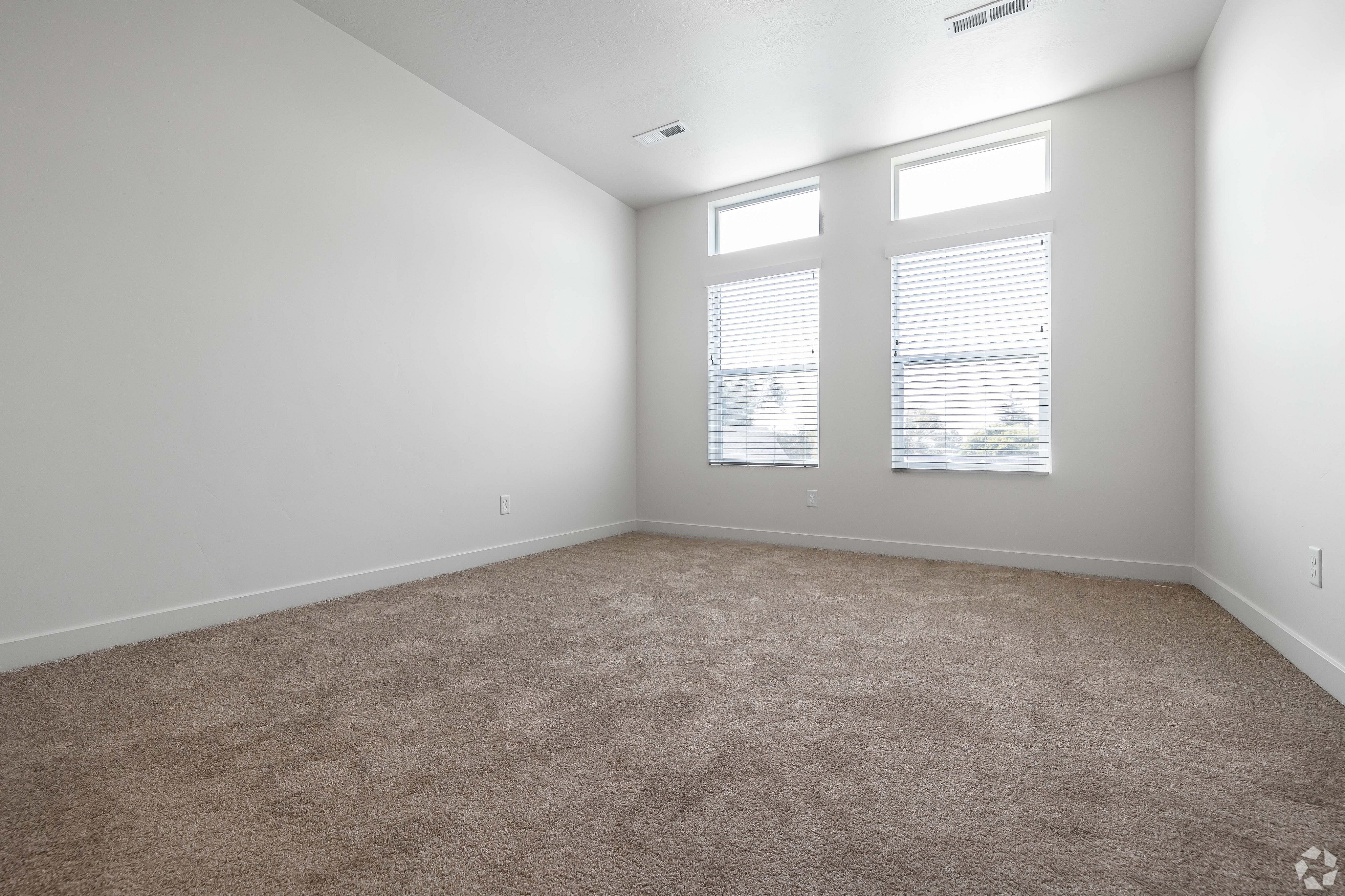 Bright and spacious bedroom with plush carpet and large windows for natural light.