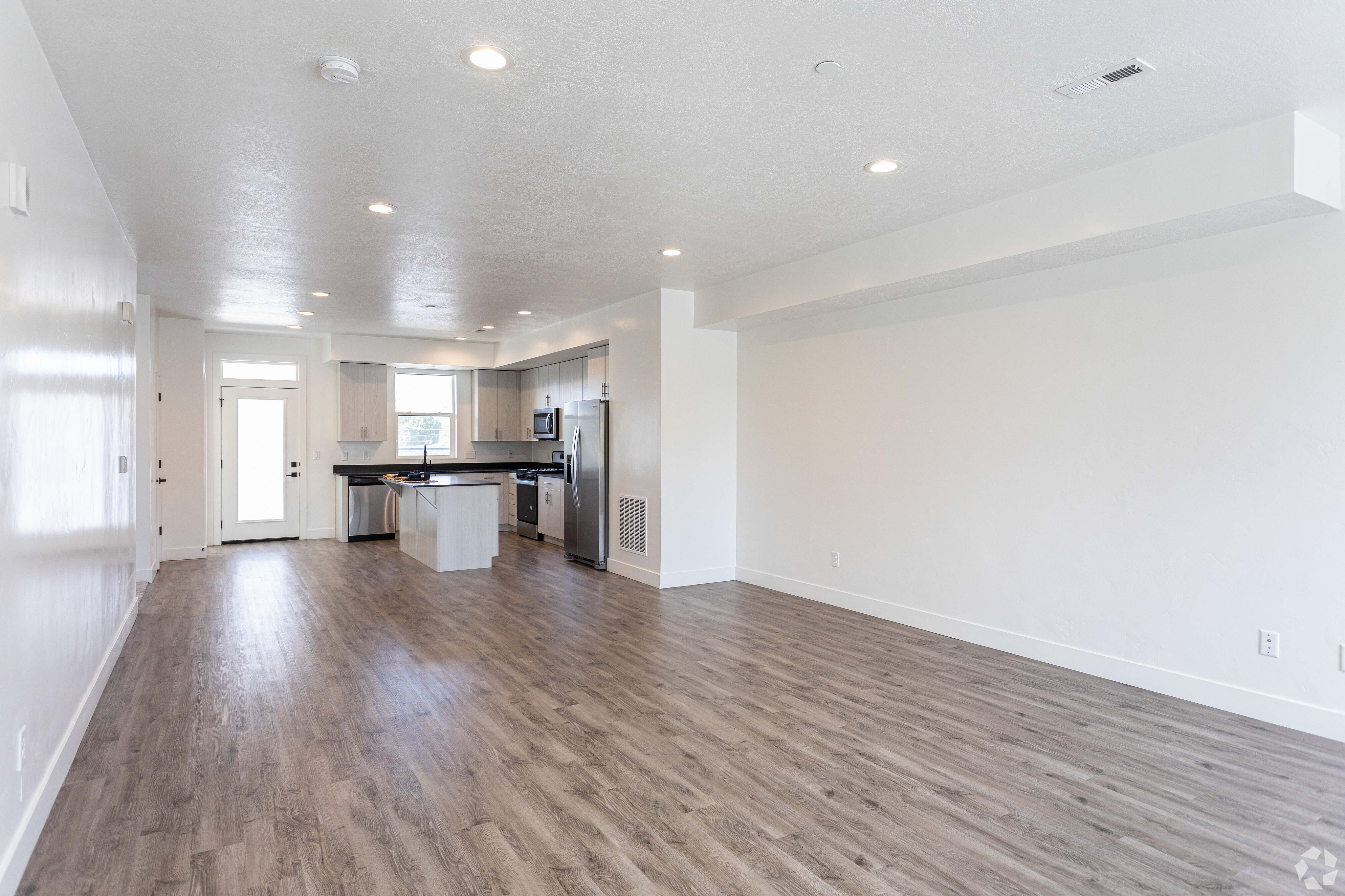 Bright and modern open-concept living area with sleek wood flooring and a stylish kitchen island, perfect for comfortable and elegant living.