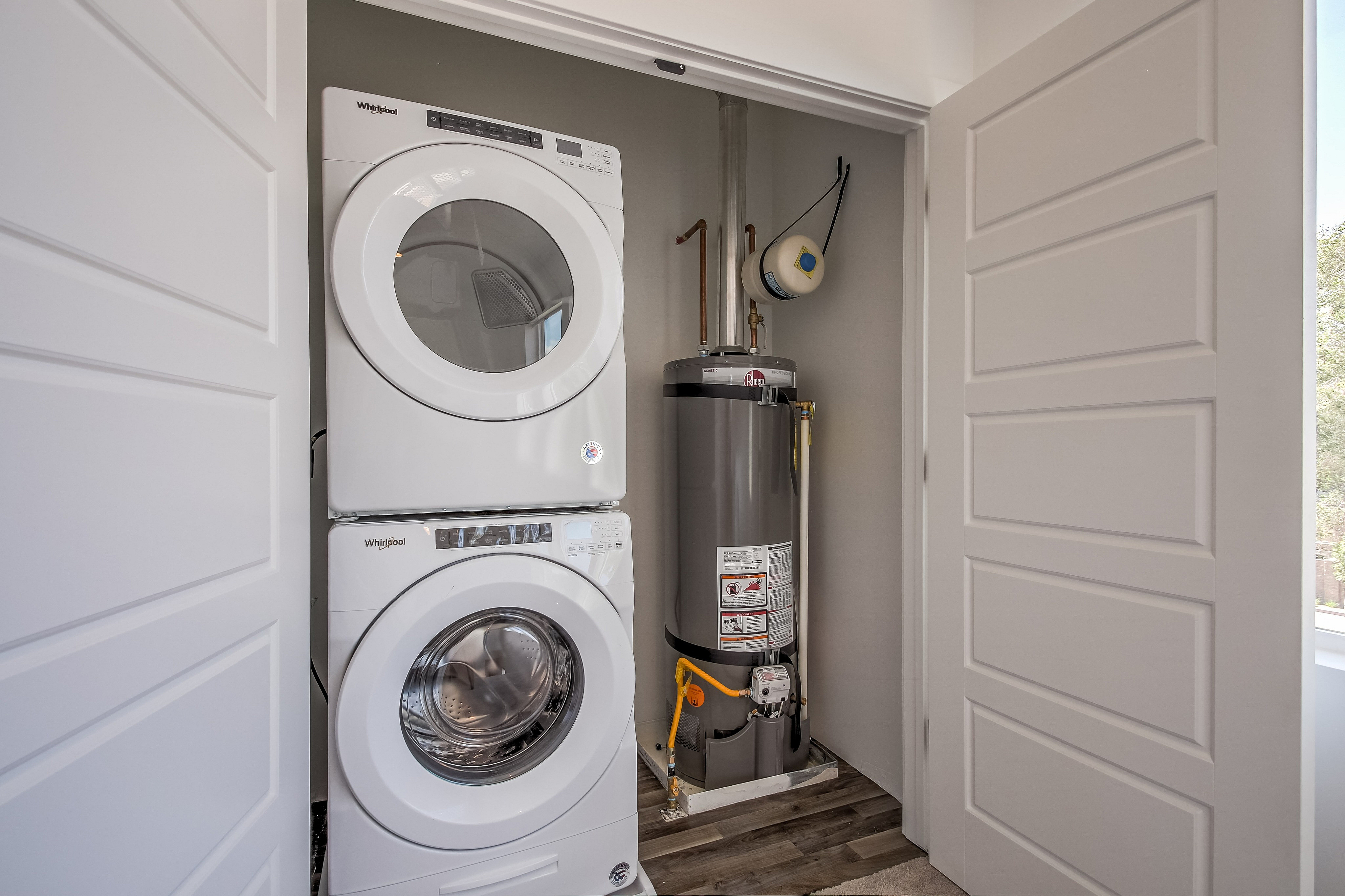 Modern laundry area featuring a stacked washer and dryer with an efficient water heater. Elegant design and convenience in one space.