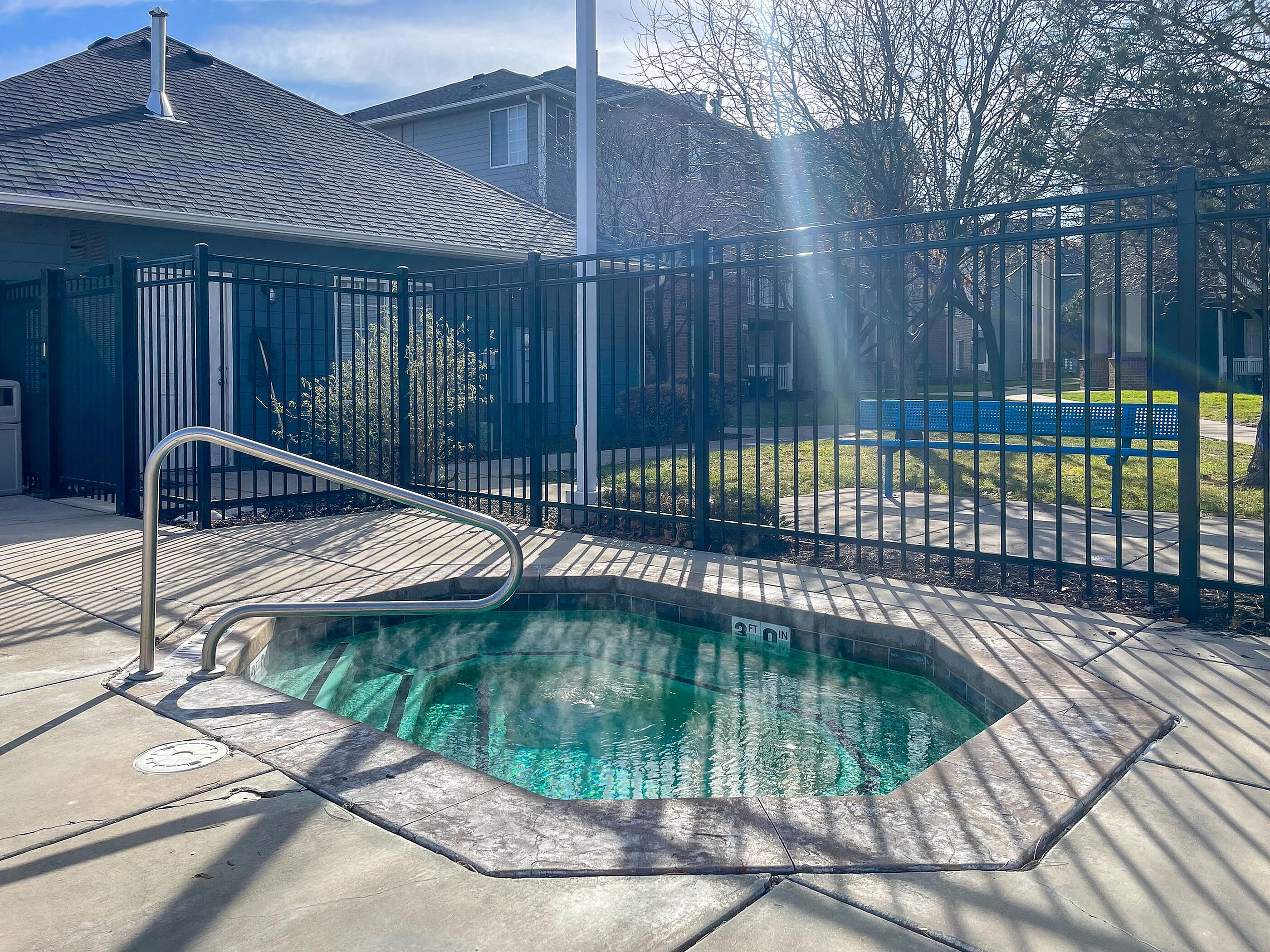 Inviting outdoor hot tub surrounded by a secure fence, bathed in warm sunlight, perfect for relaxation and enjoyment.