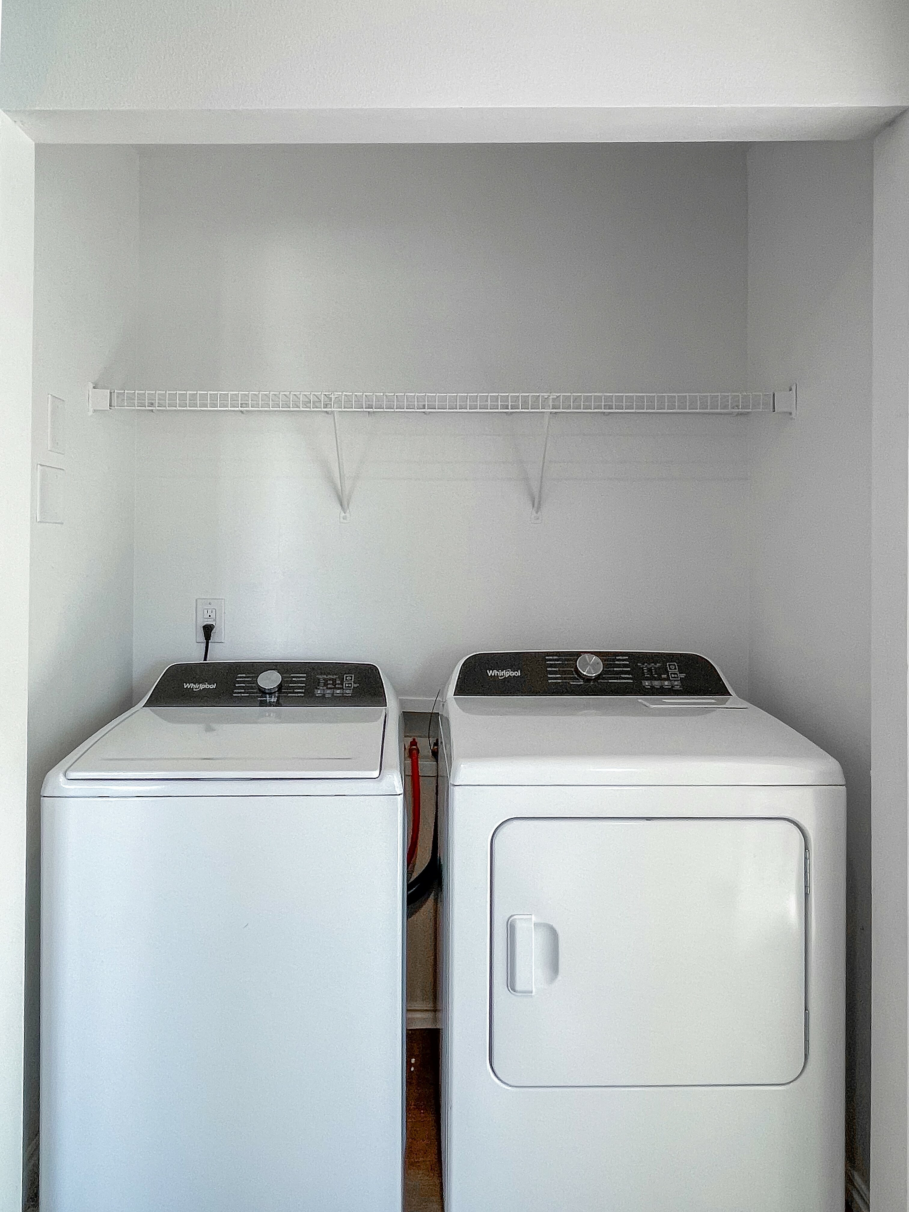 Sleek in-unit laundry nook featuring modern washer and dryer with overhead storage shelf, enhancing convenience and functionality.