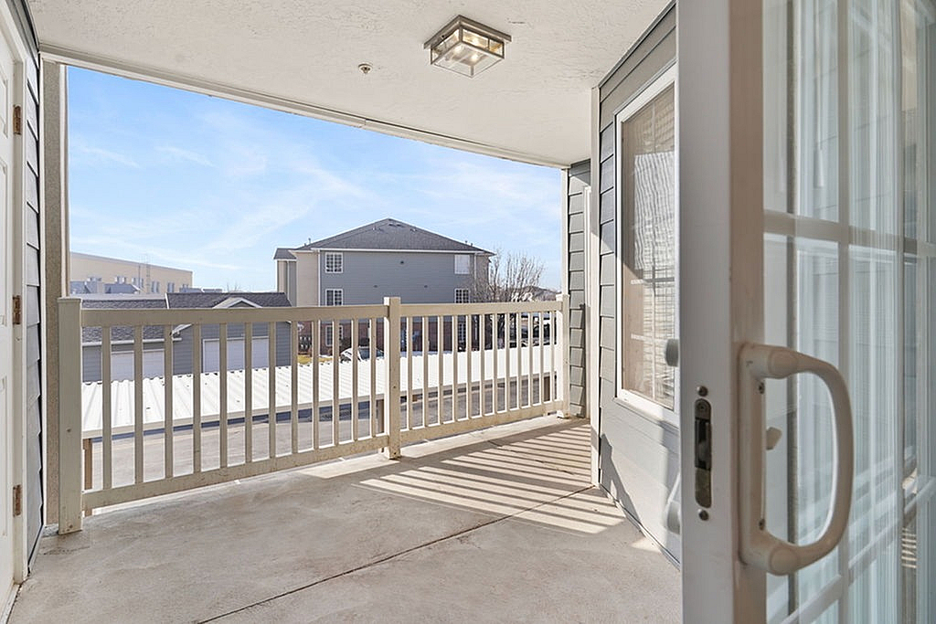 Inviting apartment balcony with elegant railing, offering a scenic view of the neighborhood and blue sky.