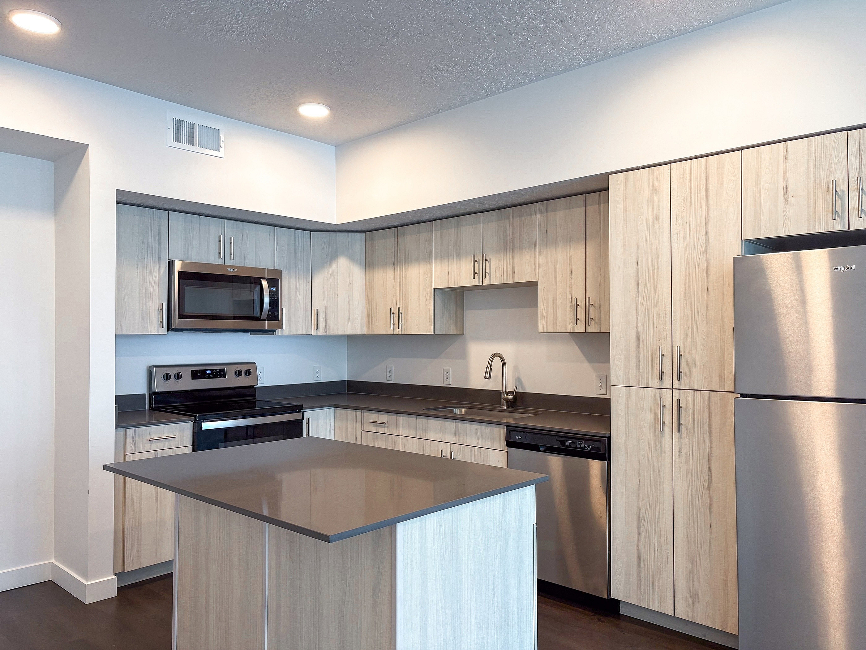 Modern kitchen with sleek stainless steel appliances, elegant light wood cabinetry, and a spacious island workspace, perfect for culinary creativity.