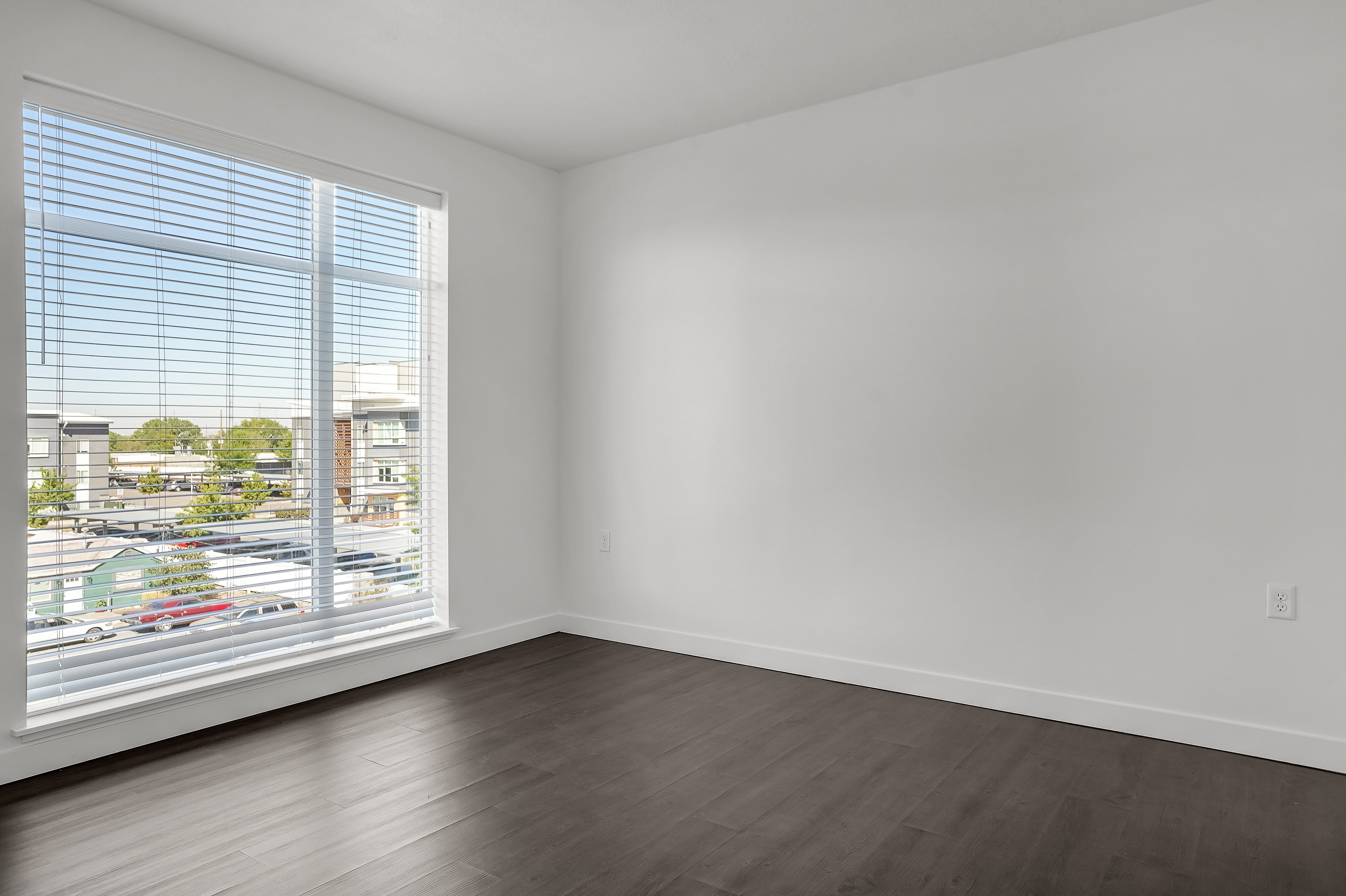 Bright, spacious room with large window and modern hardwood flooring, perfect for natural light enthusiasts.