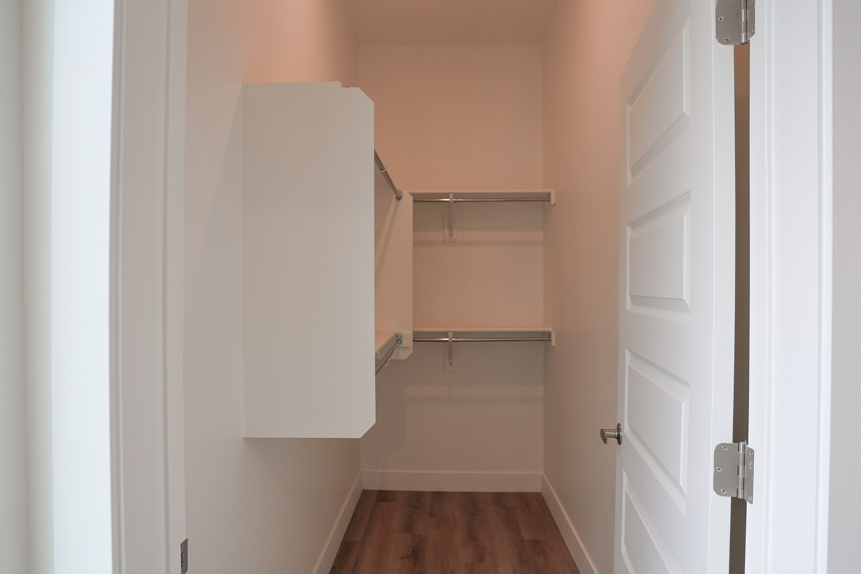 Spacious walk-in closet with elegant shelving and hardwood floors, perfect for organized storage and modern living.