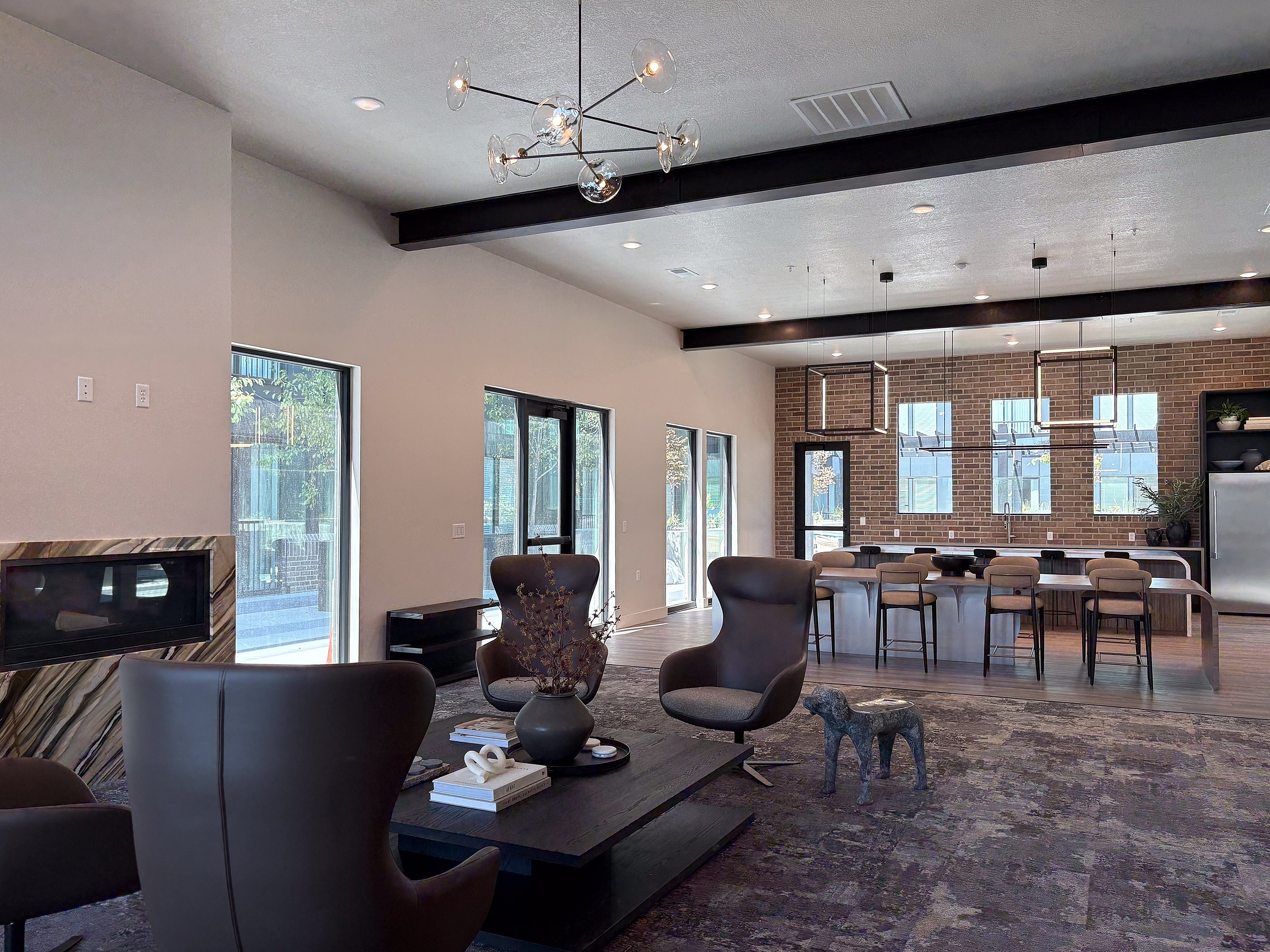 Modern open-concept living space with sleek furniture, elegant lighting, and a stylish kitchen featuring bar seating and contemporary decor.