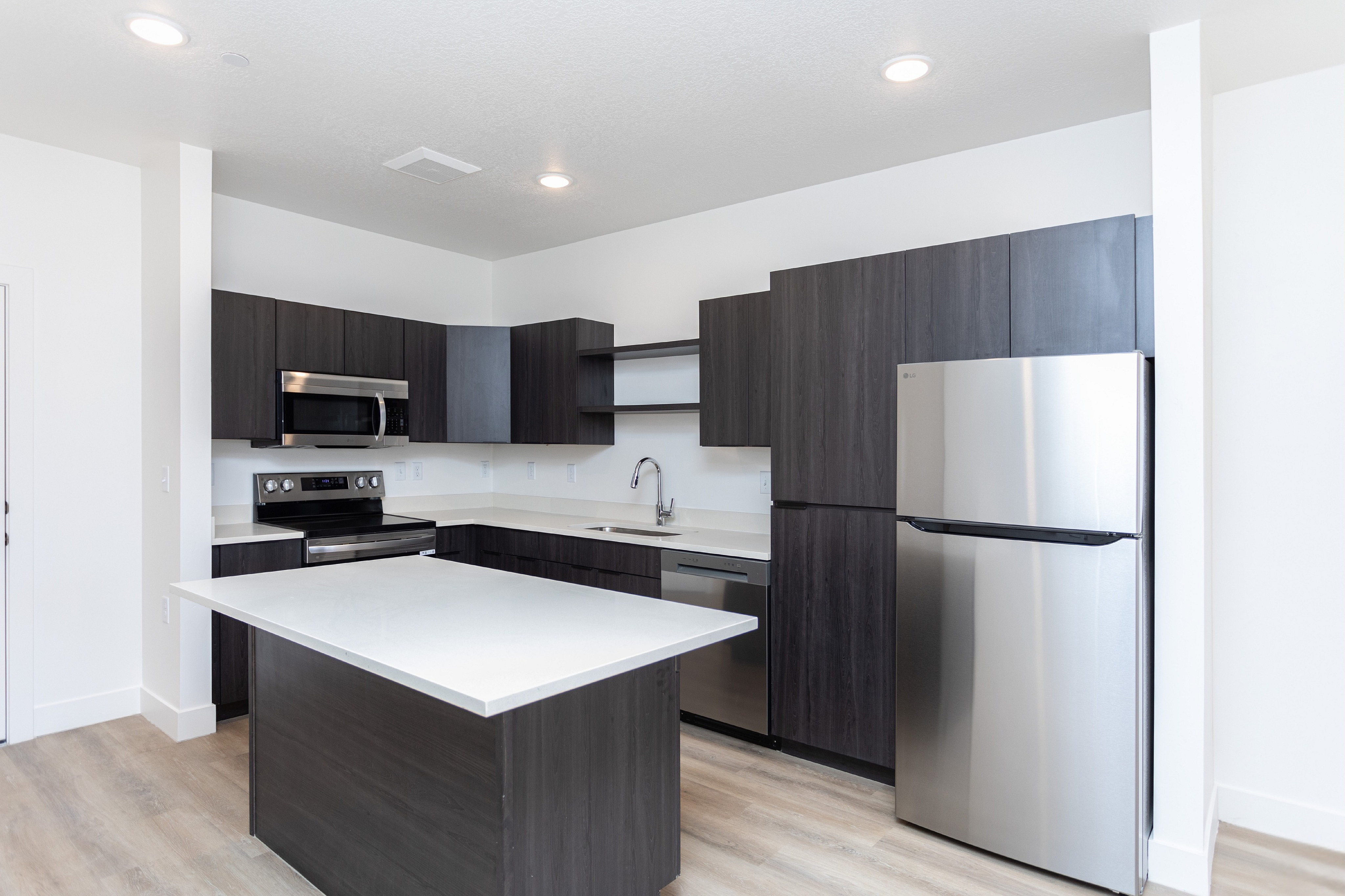 Modern kitchen with sleek dark cabinetry, stainless steel appliances, and a spacious island with bright countertops.