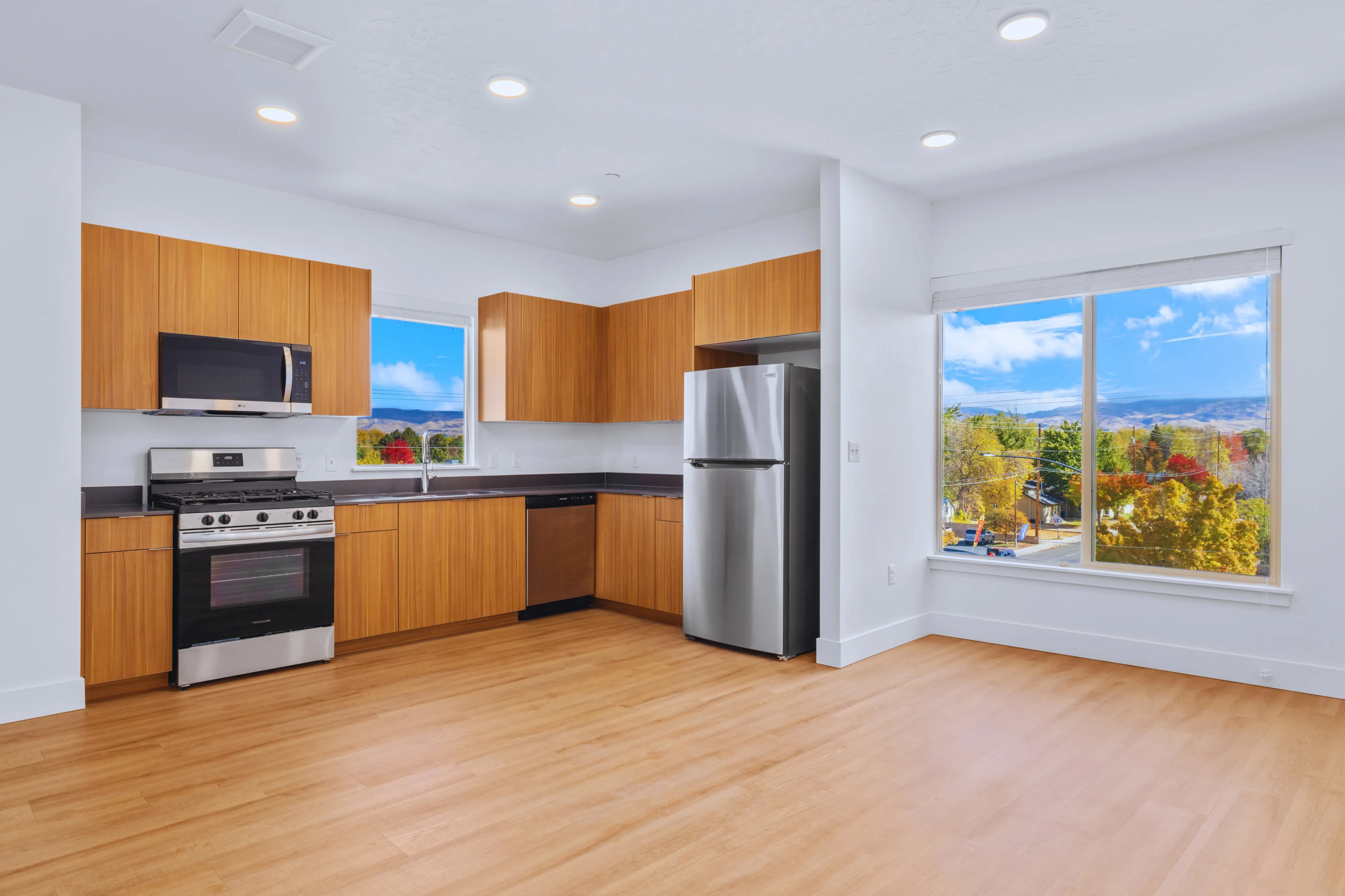 Bright and modern kitchen featuring stainless steel appliances, elegant wooden cabinets, and expansive windows with scenic views.