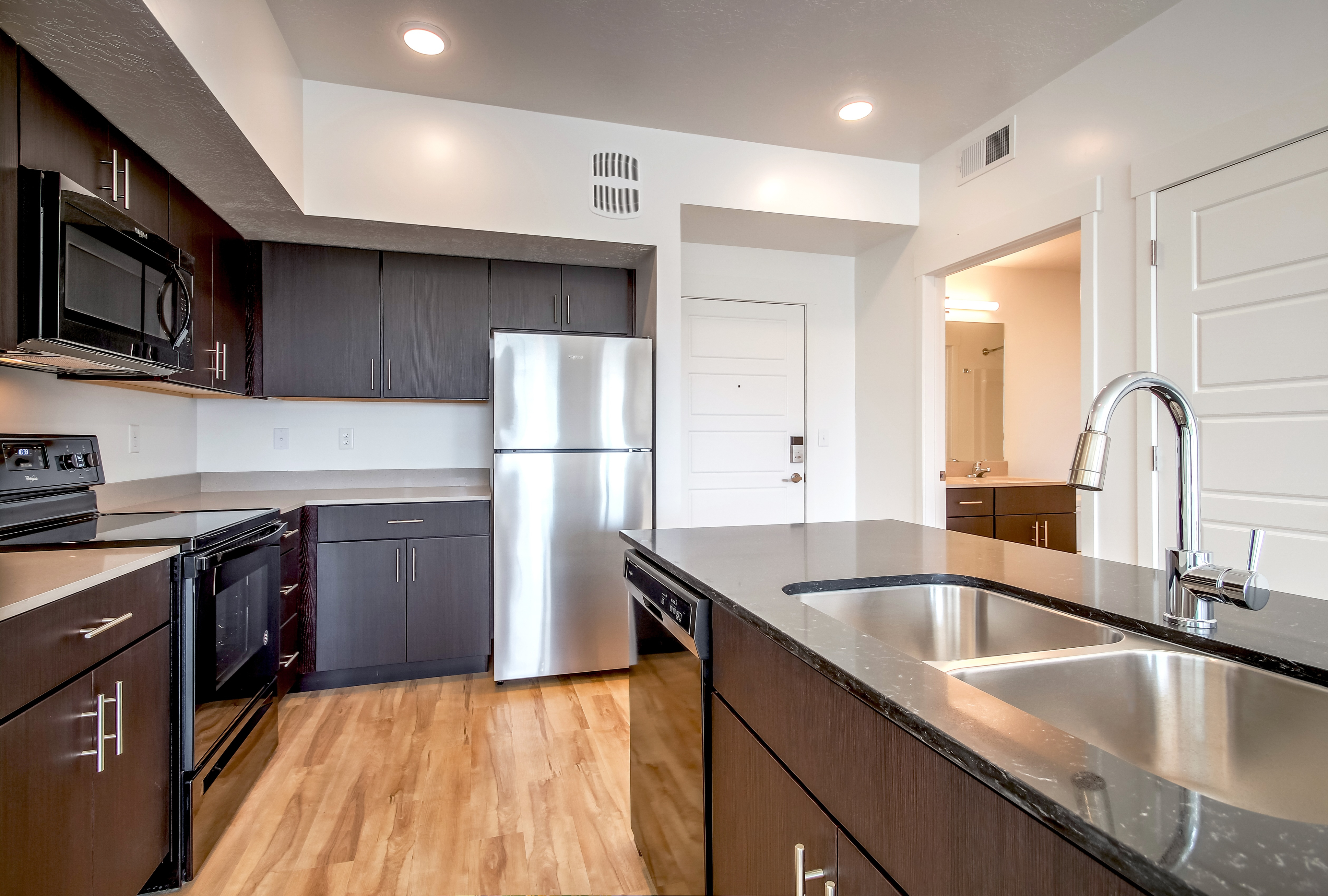 Modern kitchen with sleek dark cabinetry, stainless steel appliances, and an elegant island sink, offering a bright and inviting atmosphere.